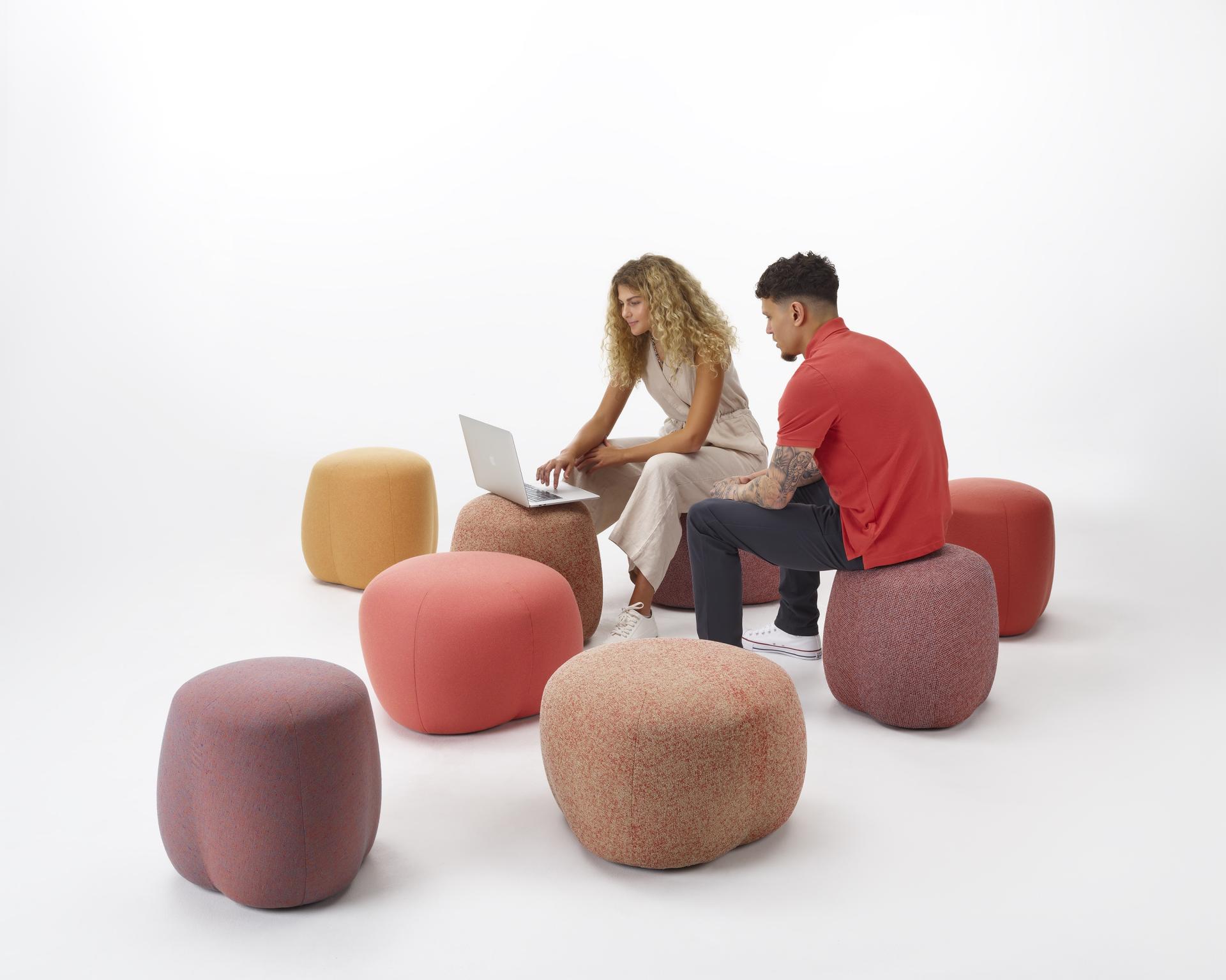 Two people interact on NaughtOne's playful Truffle poufs, showcasing vibrant colors and versatile seating design.