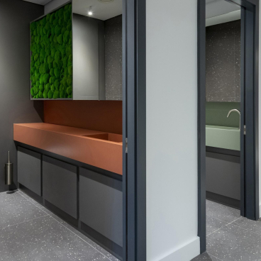 Modern restroom interior featuring Cosentino's Sunlit Days Vanities collection with green moss accents and sleek design.