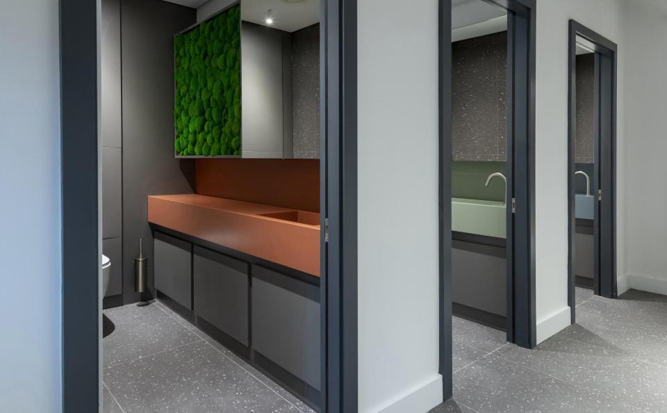 Modern restroom interior featuring Cosentino's Sunlit Days Vanities collection with green moss accents and sleek design.