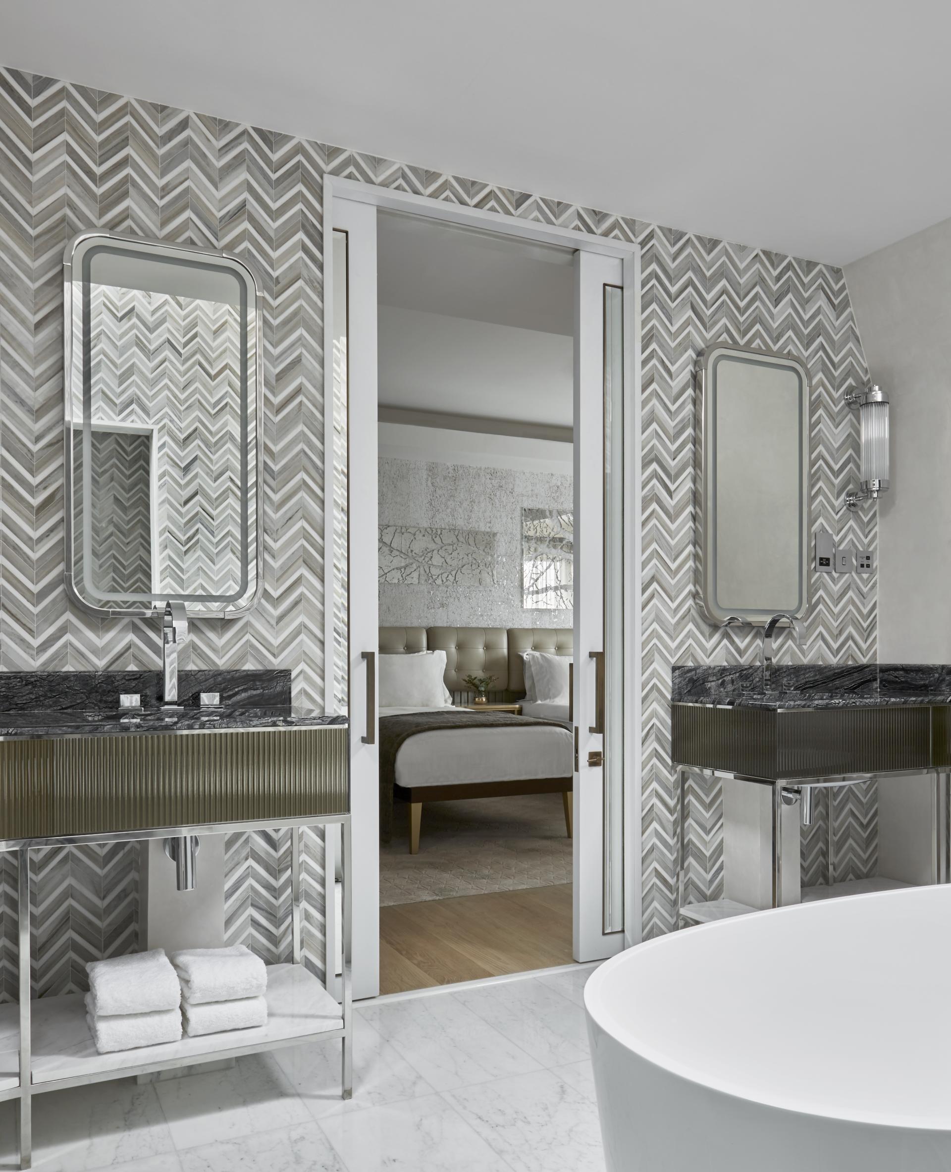 Luxurious penthouse bathroom featuring elegant chevron tile, dual mirrors, and a stylish freestanding bathtub at Mandarin Oriental London.
