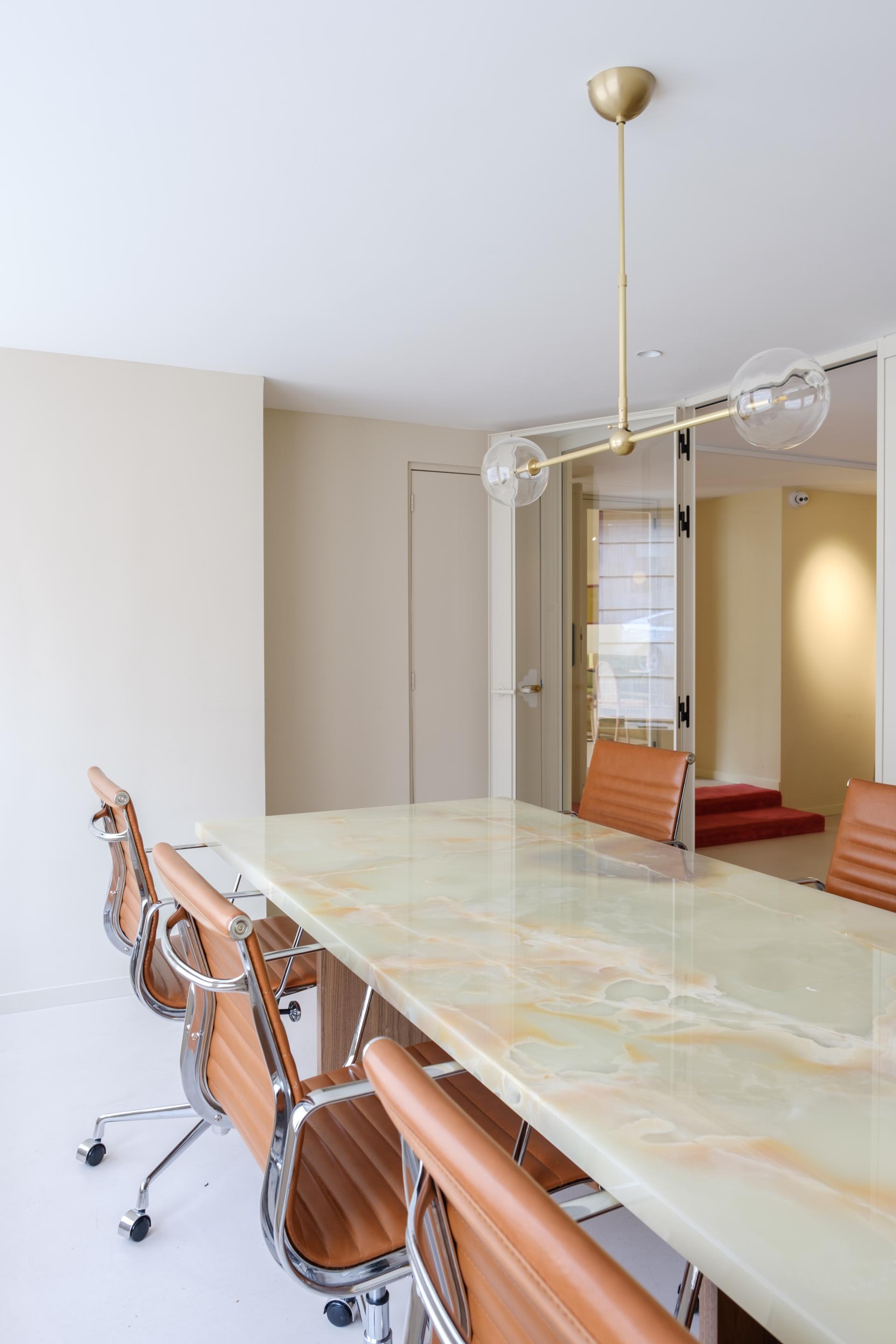 Modern conference room featuring a stunning onyx table, stylish leather chairs, and elegant lighting design by SolidNature.