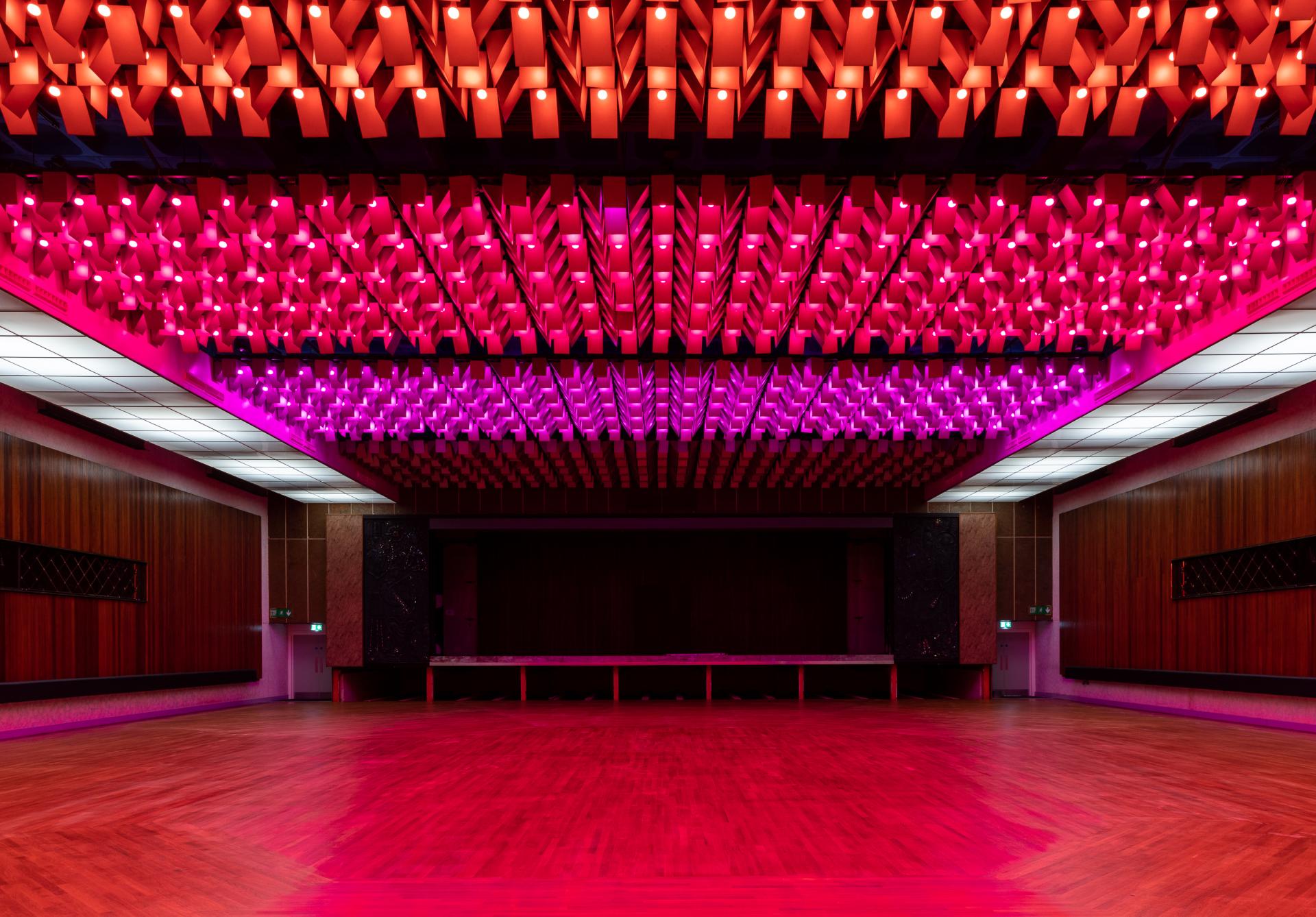 Vibrant interior of New Century venue, showcasing stunning pink and red lighting design for community events and gatherings.