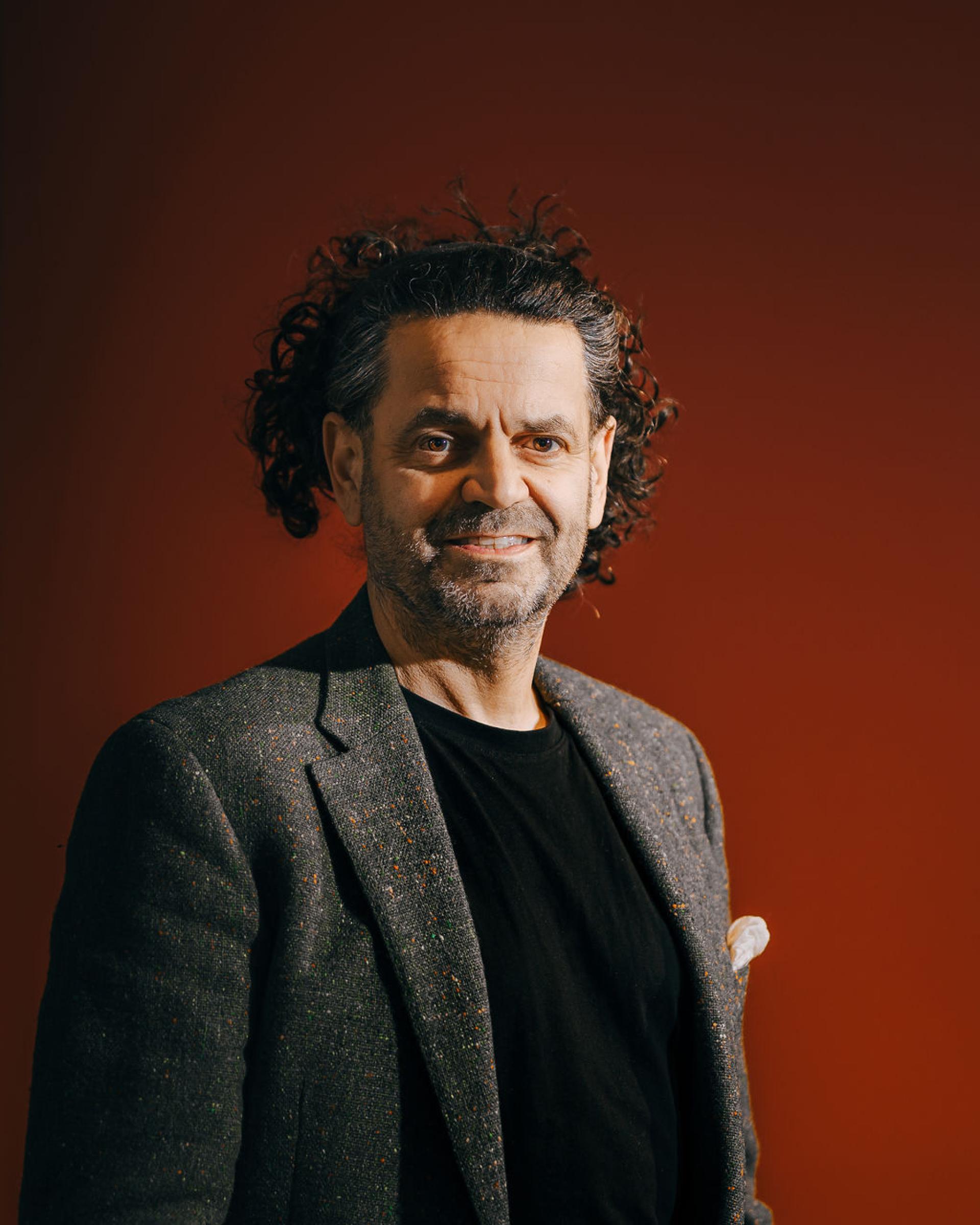 Portrait of a man with curly hair wearing a black shirt and a textured blazer, emphasizing innovation in biomaterials.