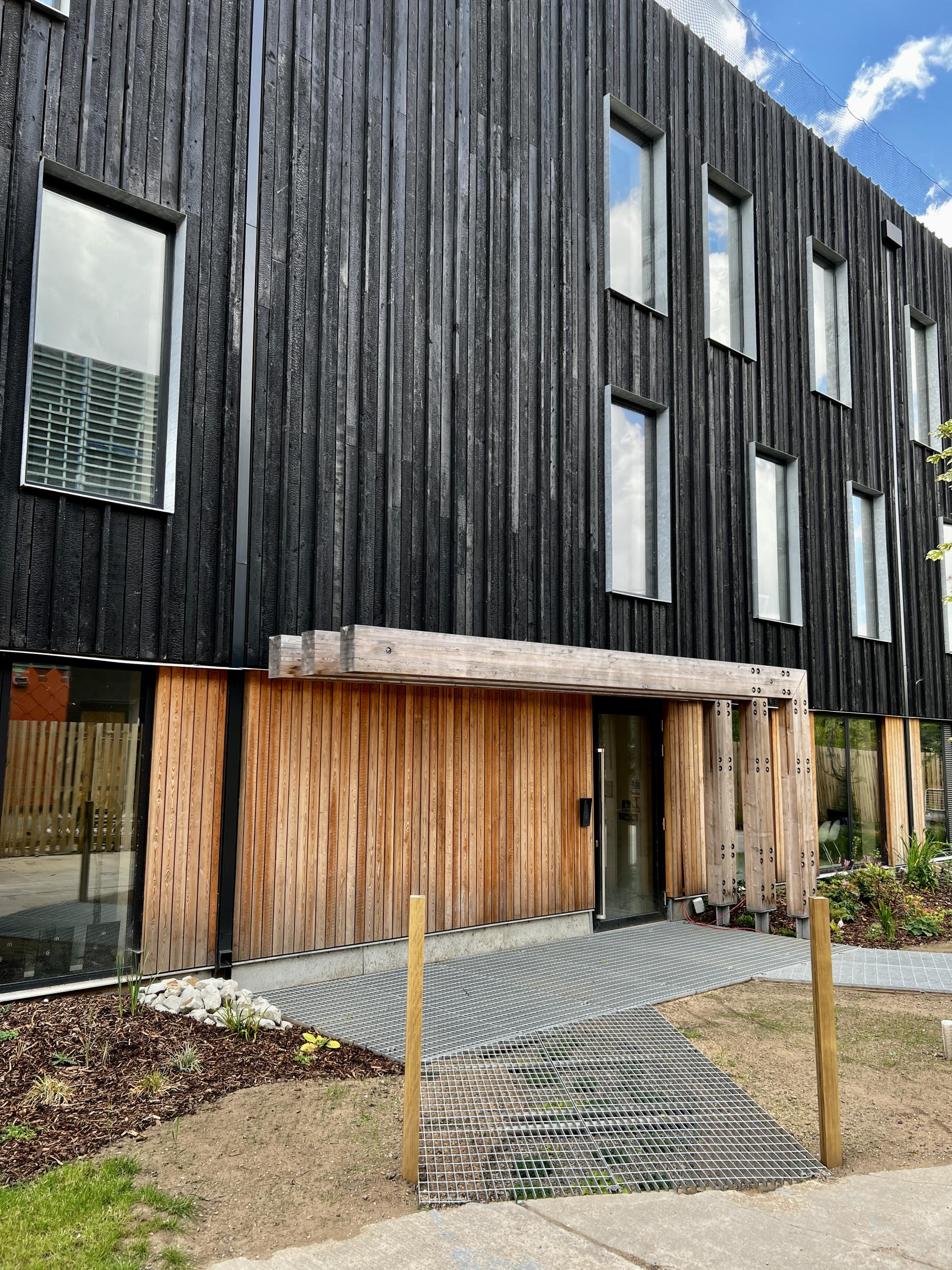 Modern net zero carbon workspace in Leeds featuring a unique wooden façade and landscaped entrance pathway.