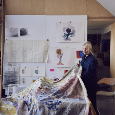 Textile artist Alice Kettle working on a vibrant fabric piece in her Manchester studio, surrounded by artwork and materials.