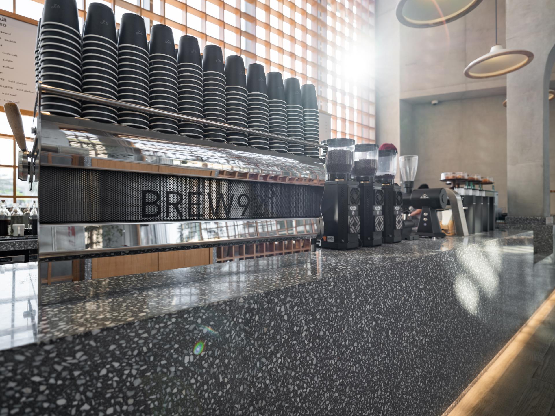 Sleek coffee bar at Brew92 featuring stacked cups, grinders, and a modern Japandi-inspired design.