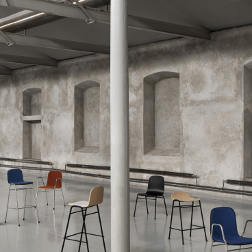 Colorful Touchwood chairs by Hem arranged in a minimalist industrial space, showcasing modern Scandinavian design.