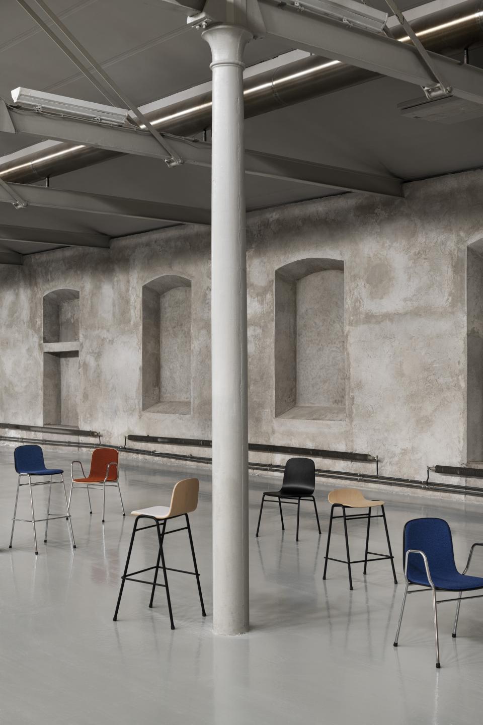 Colorful Touchwood chairs by Hem arranged in a minimalist industrial space, showcasing modern Scandinavian design.