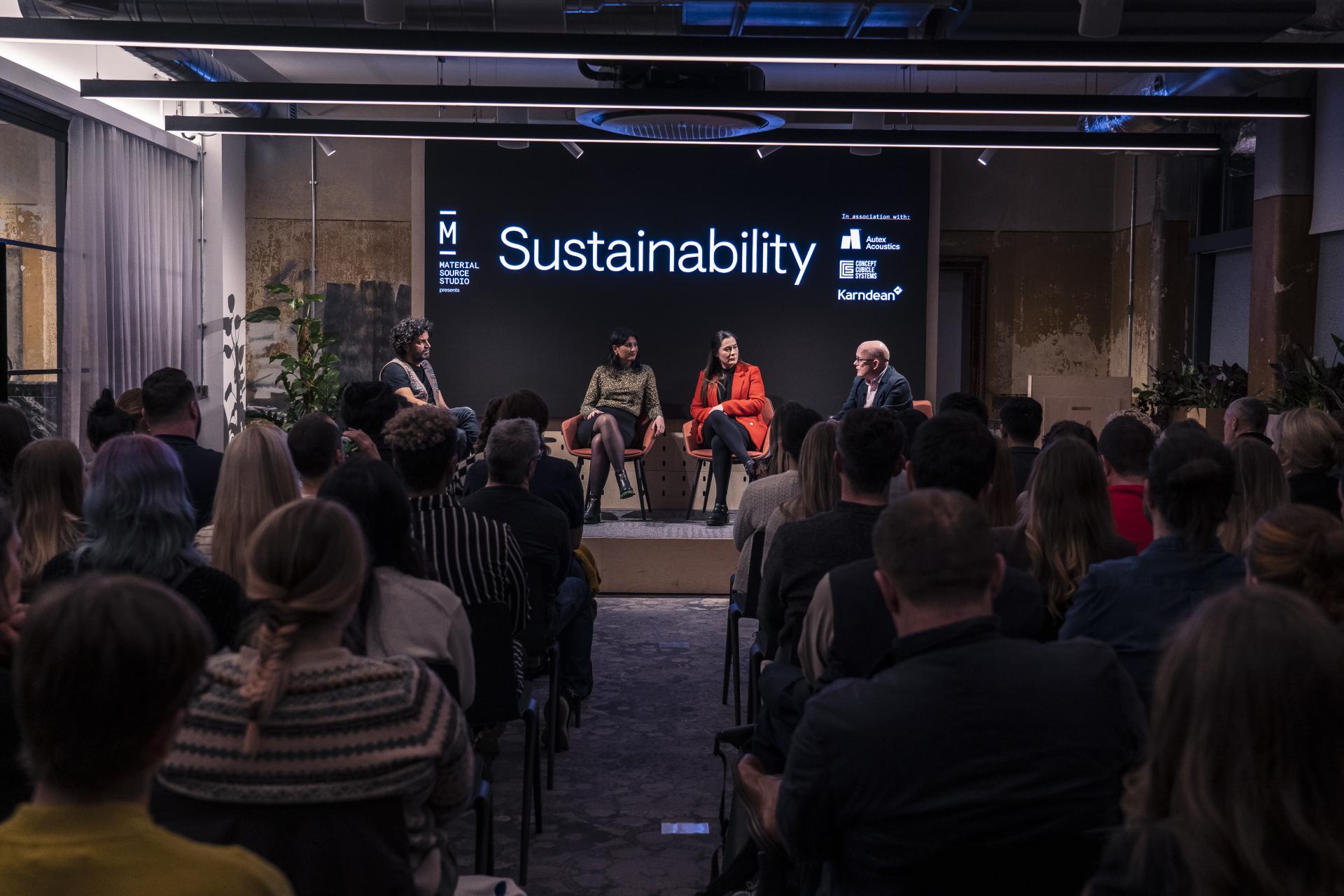 Panel discussion on sustainability featuring four speakers at the Material Source Studio event, with an engaged audience in attendance.