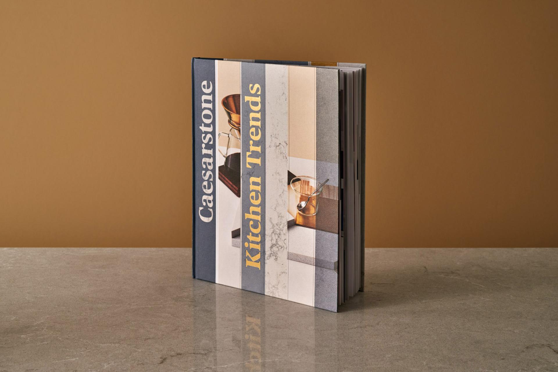 Caesarstone's "Kitchen Trends" book showcasing premium quartz design ideas against a warm, neutral backdrop.