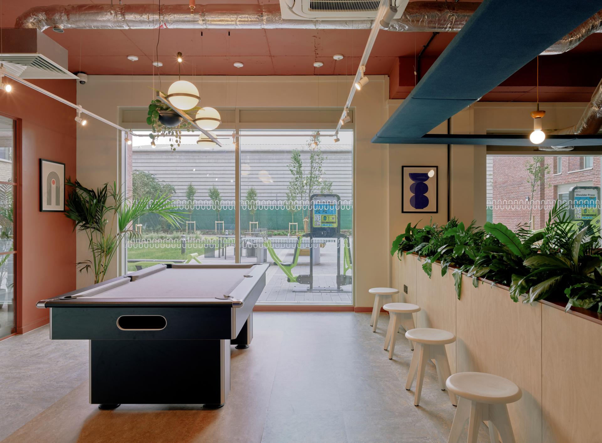 Modern game room featuring a pool table, vibrant decor, and lush plants, showcasing Enso's inviting community space in Colchester.