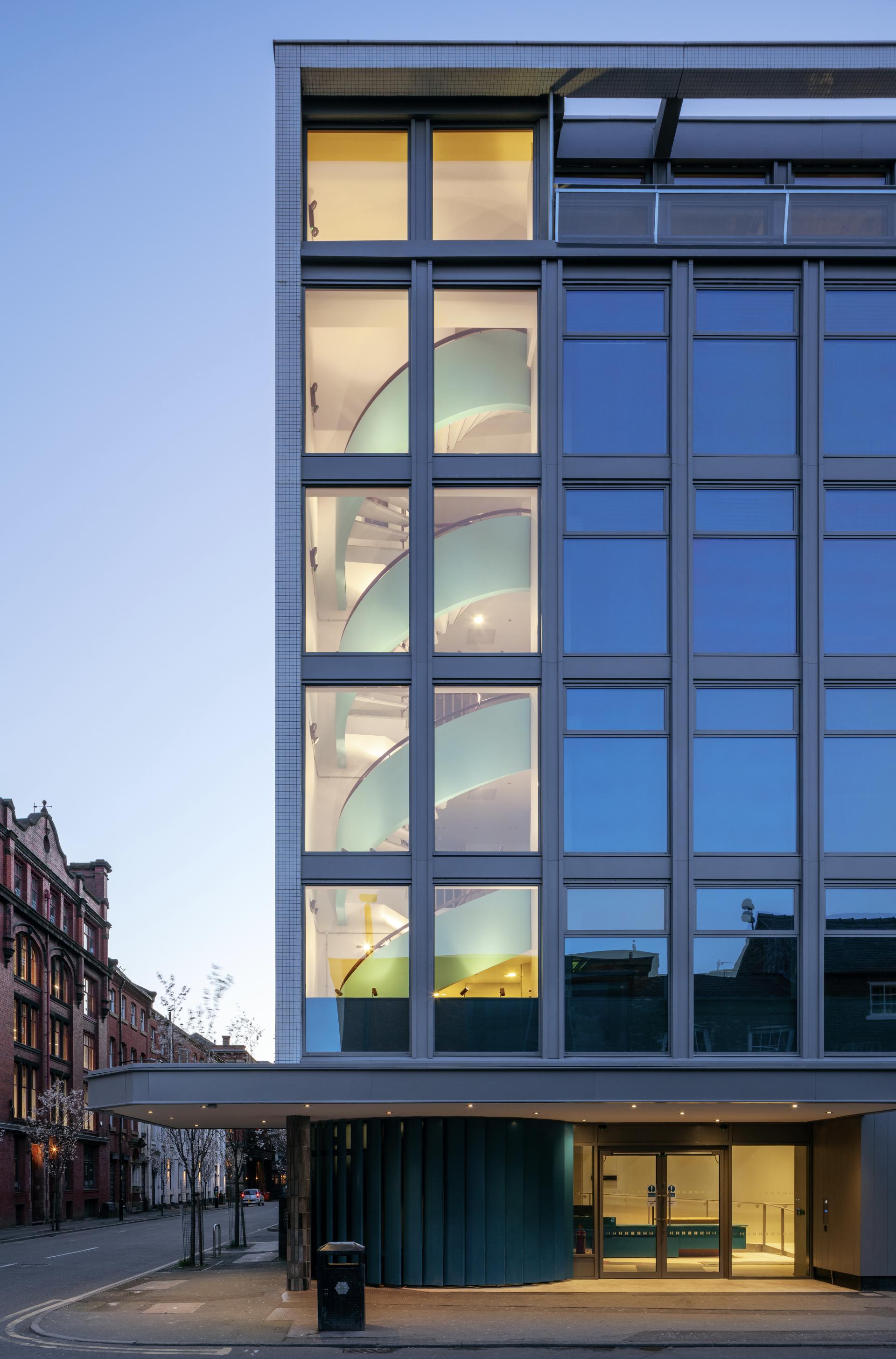 Modern architectural design featuring a glass facade with distinctive spiral staircase and contemporary entrance, showcasing Buttress's innovative approach.