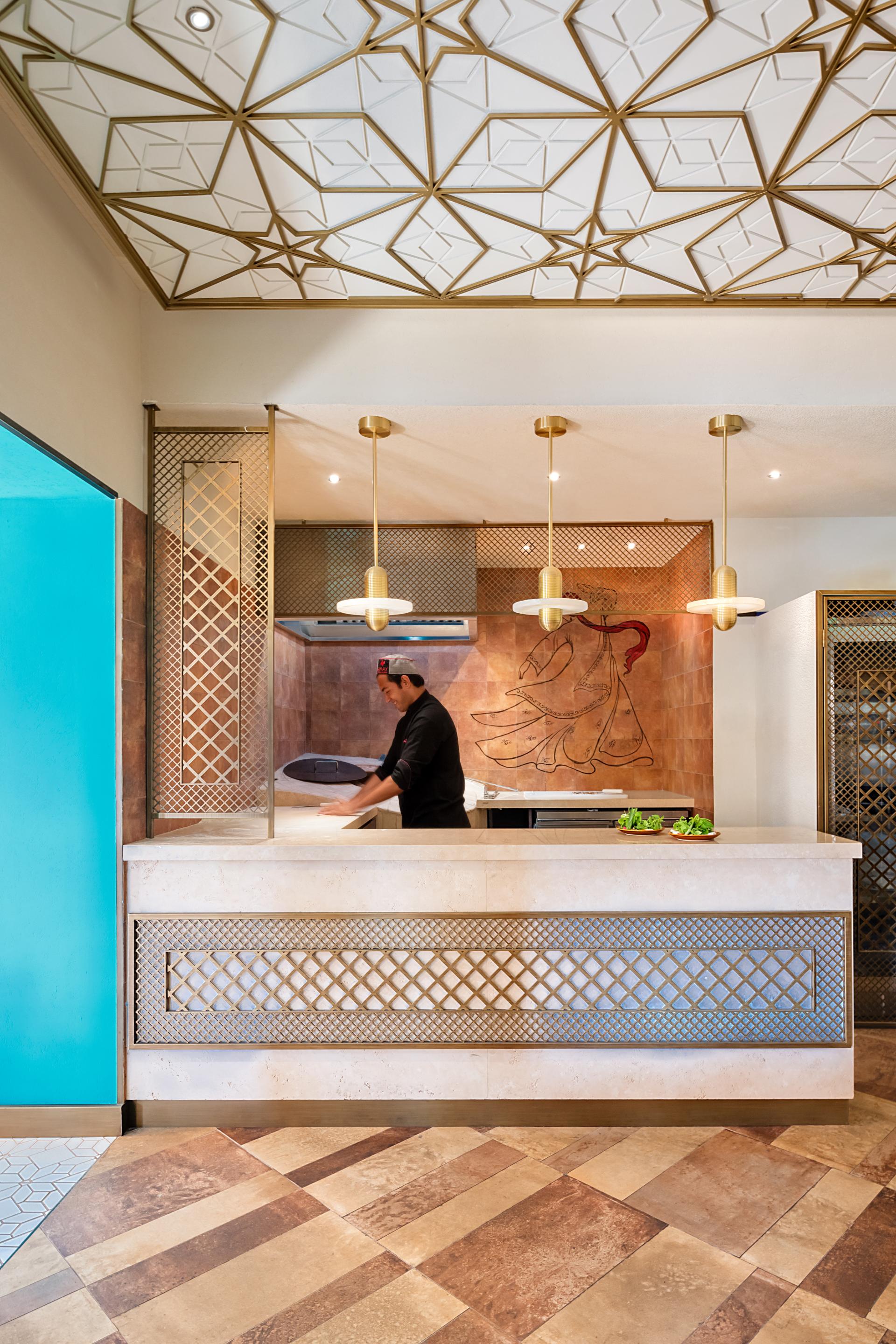 Modern Persian restaurant Anar's renovated kitchen showcasing intricate ceiling design and chef preparing dishes in Dubai.