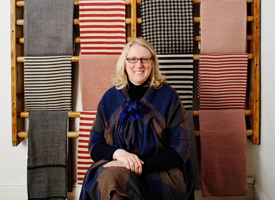 Polly Leonard, founder of Selvedge magazine, poses in front of colorful textiles, showcasing raw design talent in the industry.