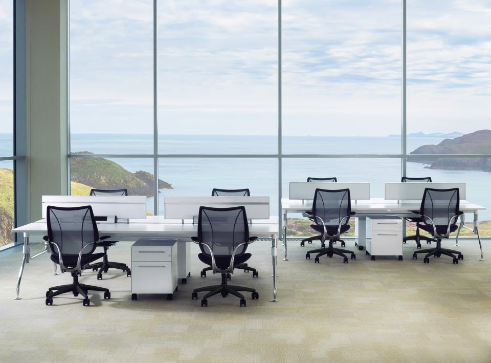 Modern office workspace with ergonomic chairs and desks, featuring panoramic ocean views, emphasizing inspiring workspace design.