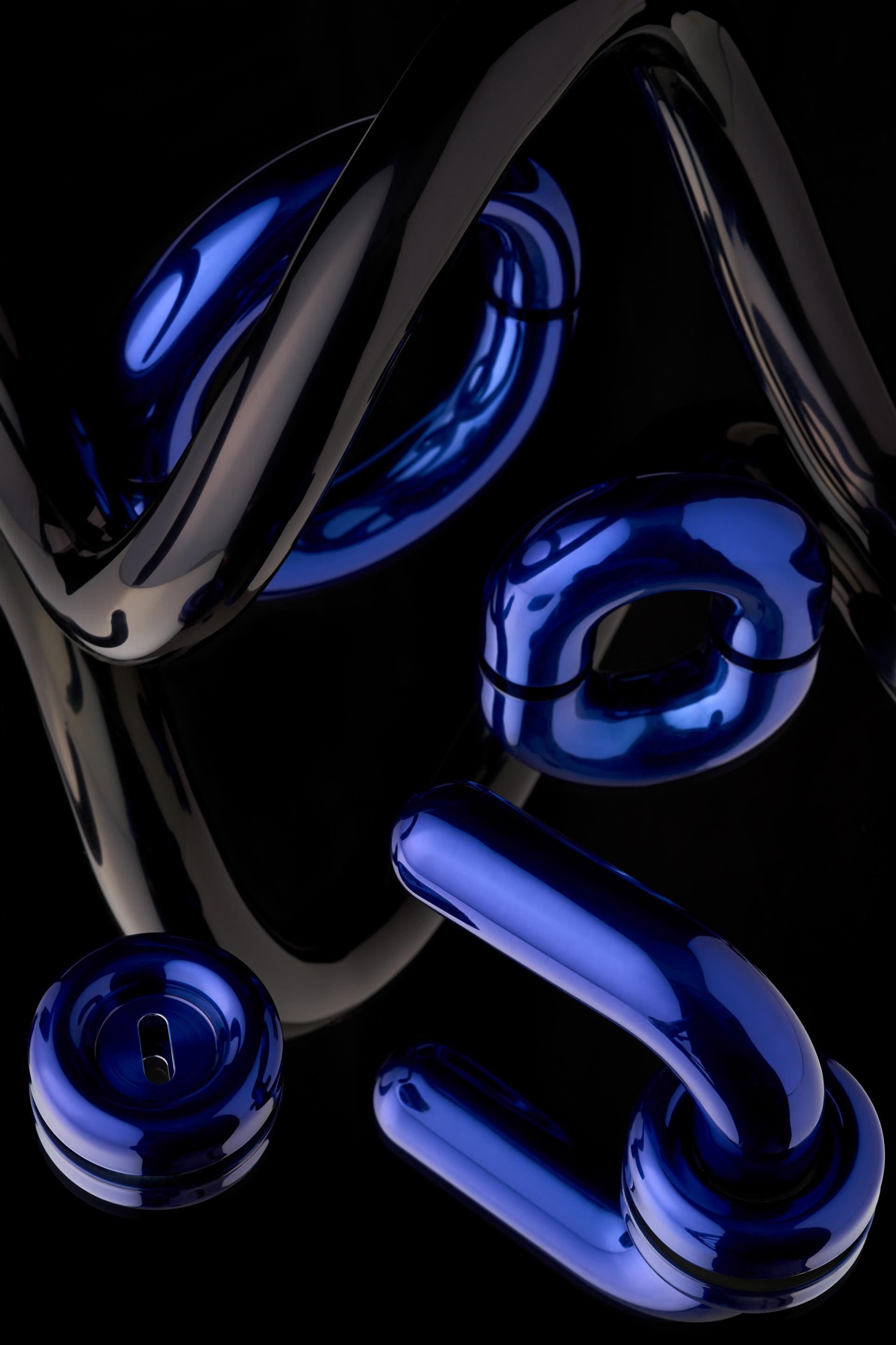 Tom Dixon's architectural ironmongery collection features sleek, modern designs in blue and black finishes against a dark background.
