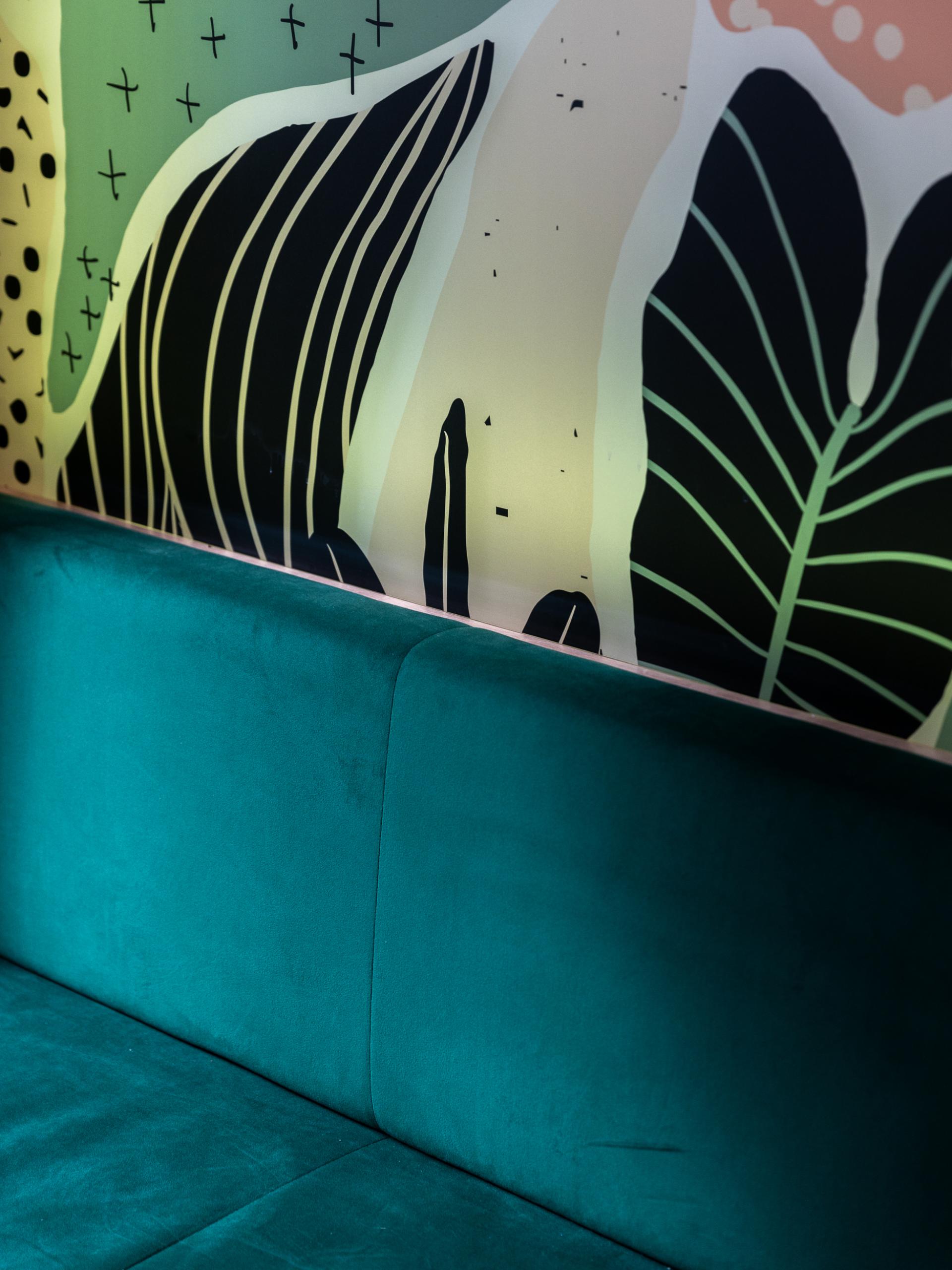Vibrant patterned wall art behind a plush teal sofa, highlighting Sheila Bird Studio's mood-boosting design at Runway East.
