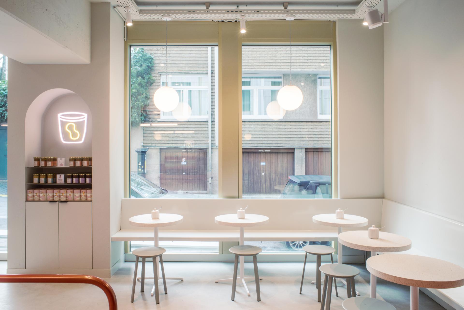 Modern café interior featuring minimalist design, light furnishings, and large windows at the new Le Toison d’Or building.