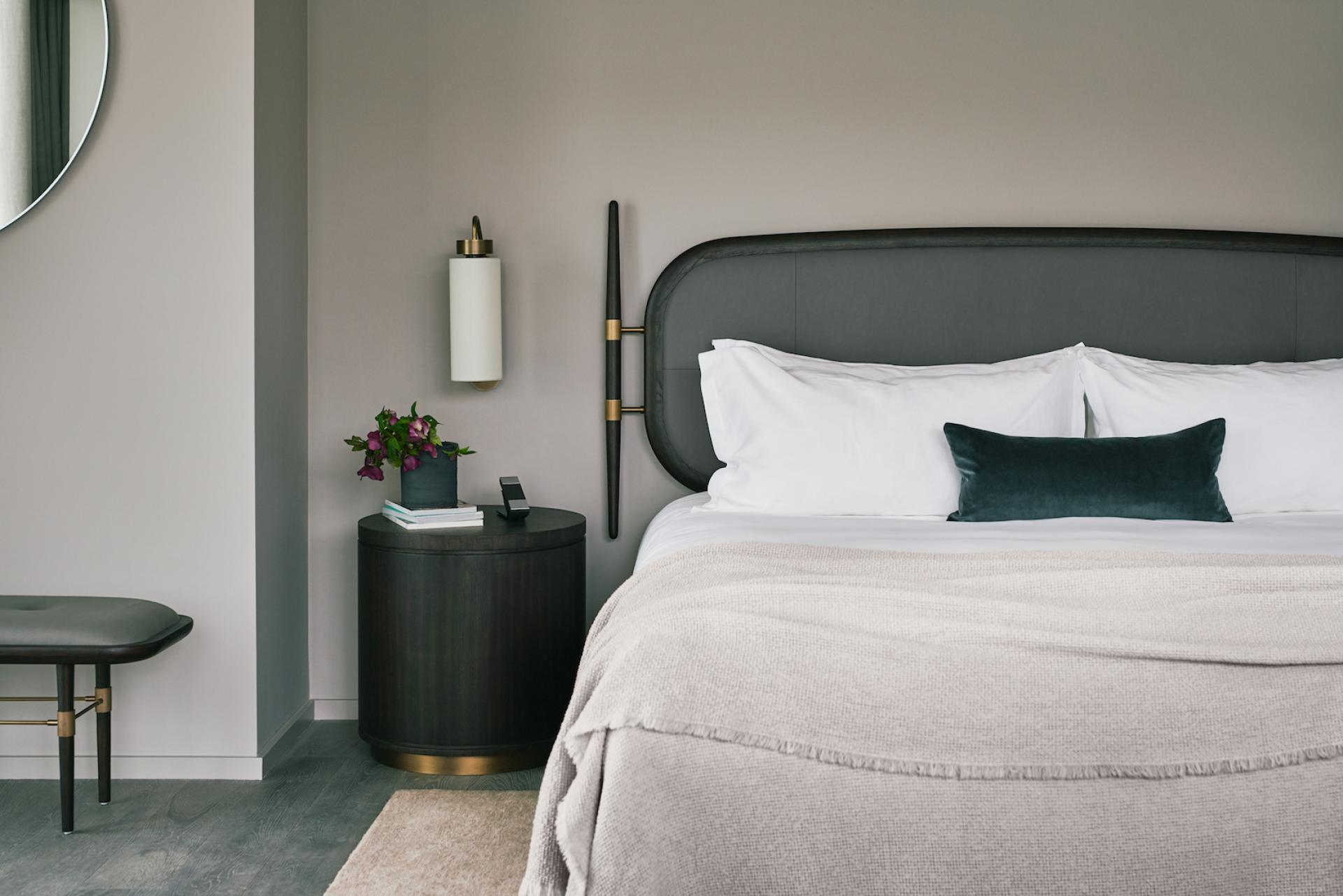 Stylish hotel bedroom featuring modern design elements, comfortable bedding, and a floral arrangement, showcasing luxury hospitality.