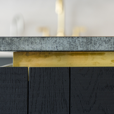 Contemporary kitchen island featuring Caesarstone countertop, brass detailing, and textured black wood cabinetry in An Actual Kitchen.