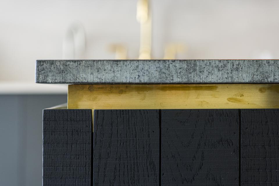 Contemporary kitchen island featuring Caesarstone countertop, brass detailing, and textured black wood cabinetry in An Actual Kitchen.
