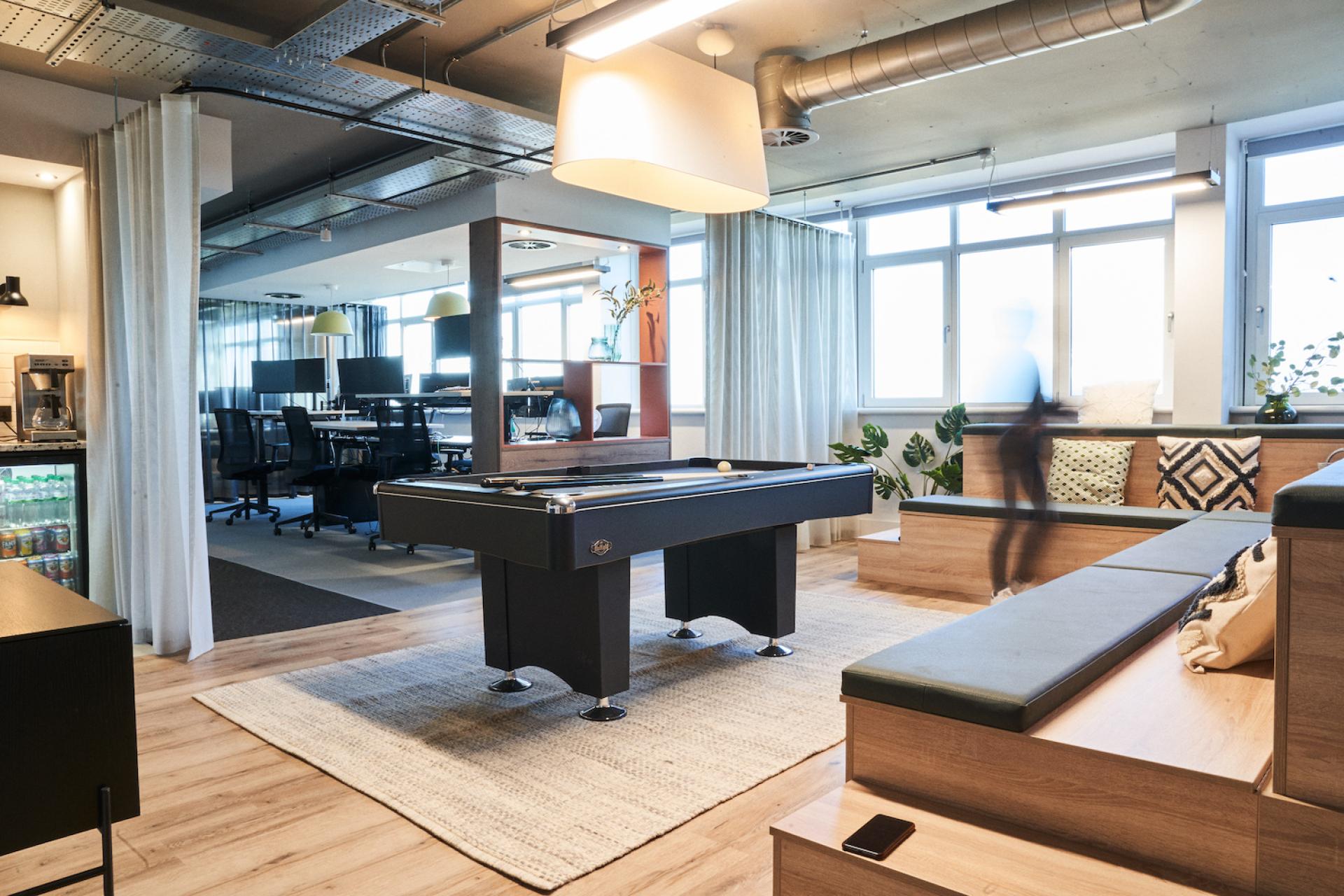 Stylish interior design featuring a pool table, modern workspaces, plants, and inviting seating area in Jolie Studio.