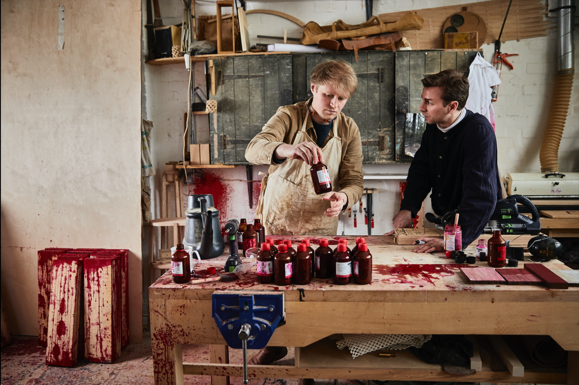 Craftsmen in a studio preparing red oak materials for the Blushing Bar installation at Milan Design Week.