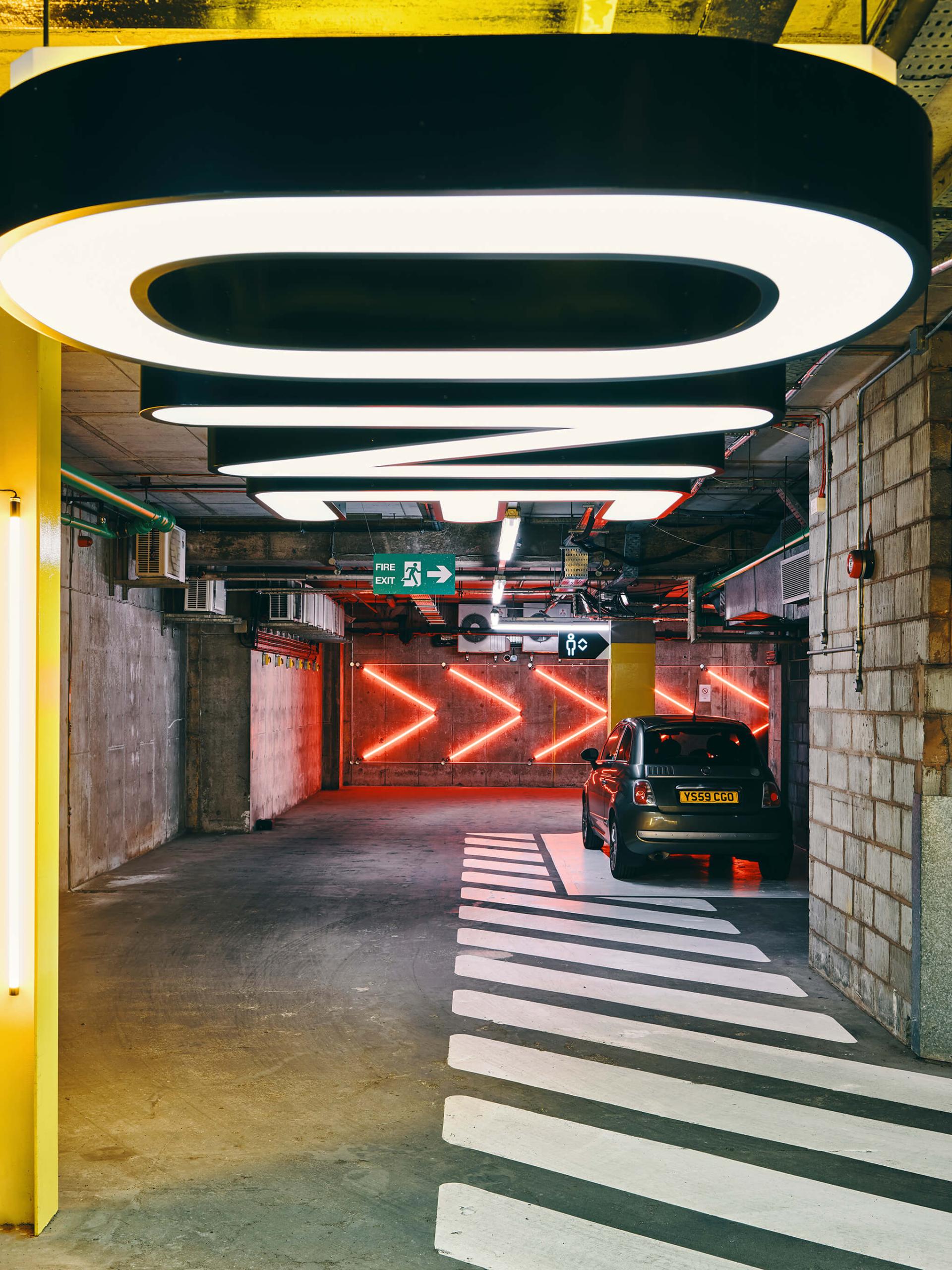 Modern parking garage with illuminated signs and lanes, showcasing design elements that influence urban architecture and commercial spaces.