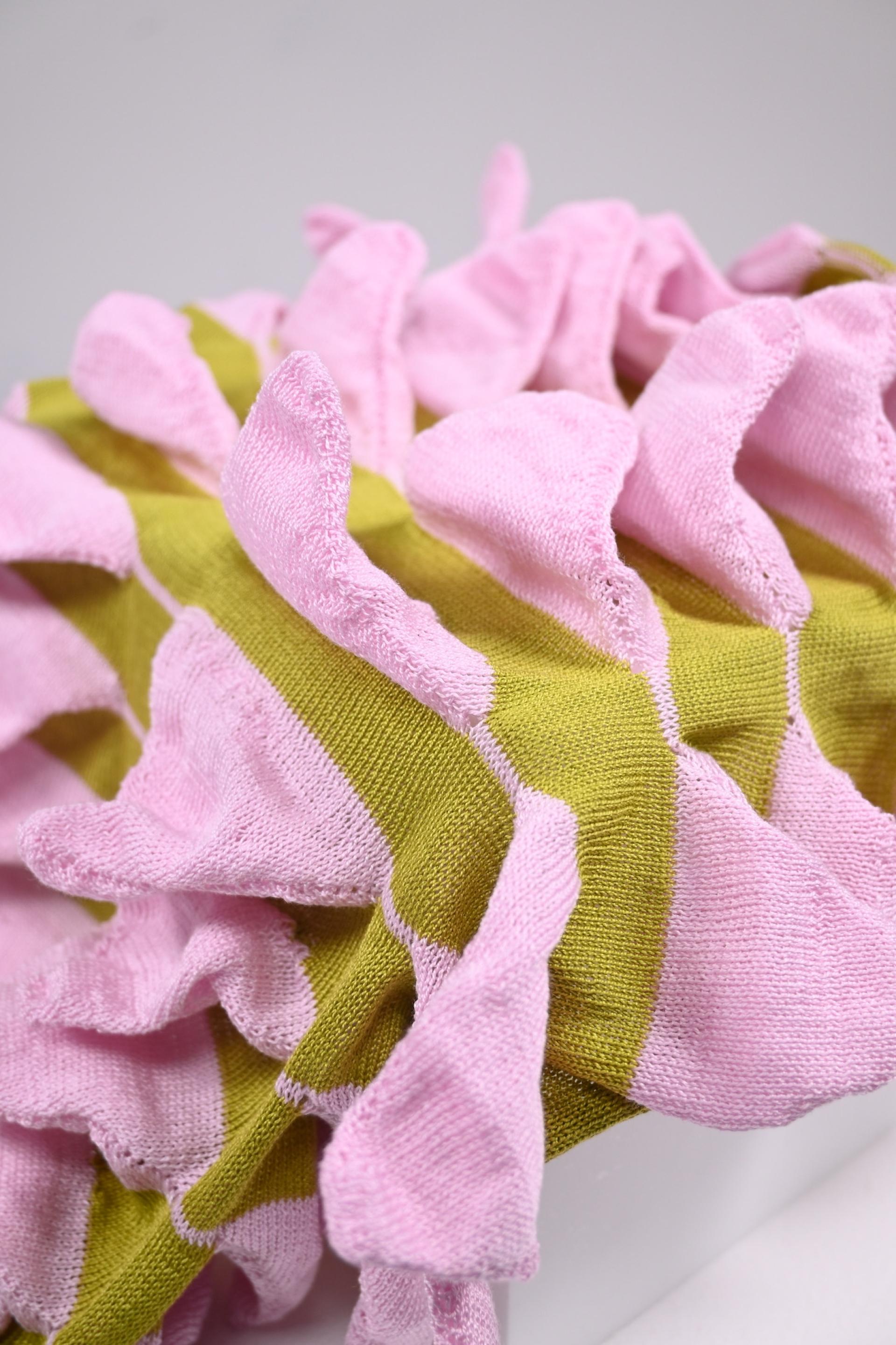 Colorful textile art piece featuring ruffled pink and green fabric, showcasing innovative design from Manchester School of Art graduates.