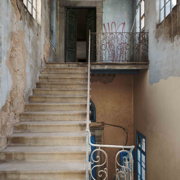 Interior view of BAYT K, showcasing 19th-century architecture, a staircase, and intricate ironwork in a historic Lebanese house.