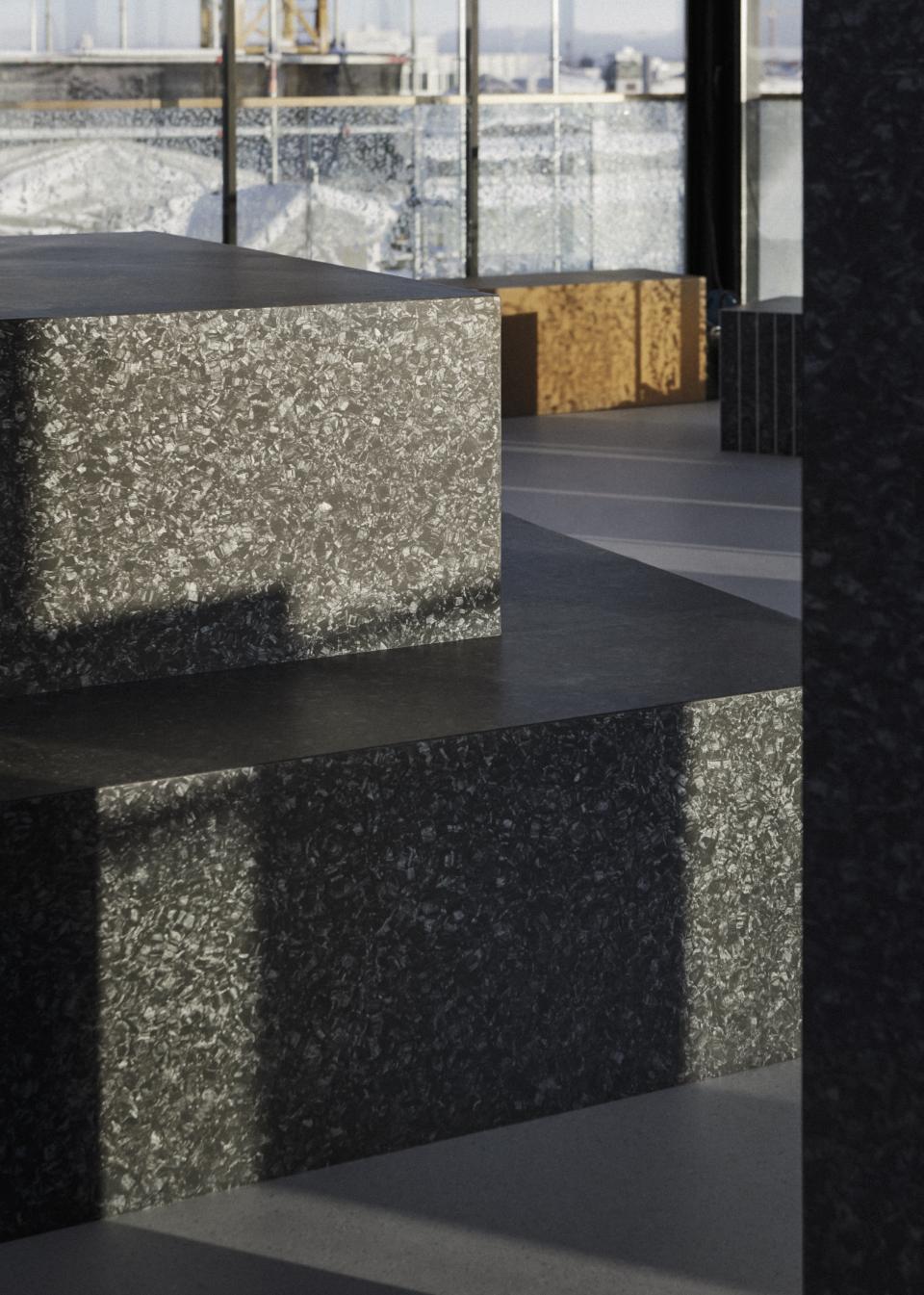 Sleek, dark stone surfaces and flowing shapes create a modern winter exhibition space in Stockholm's Snowtopped event.