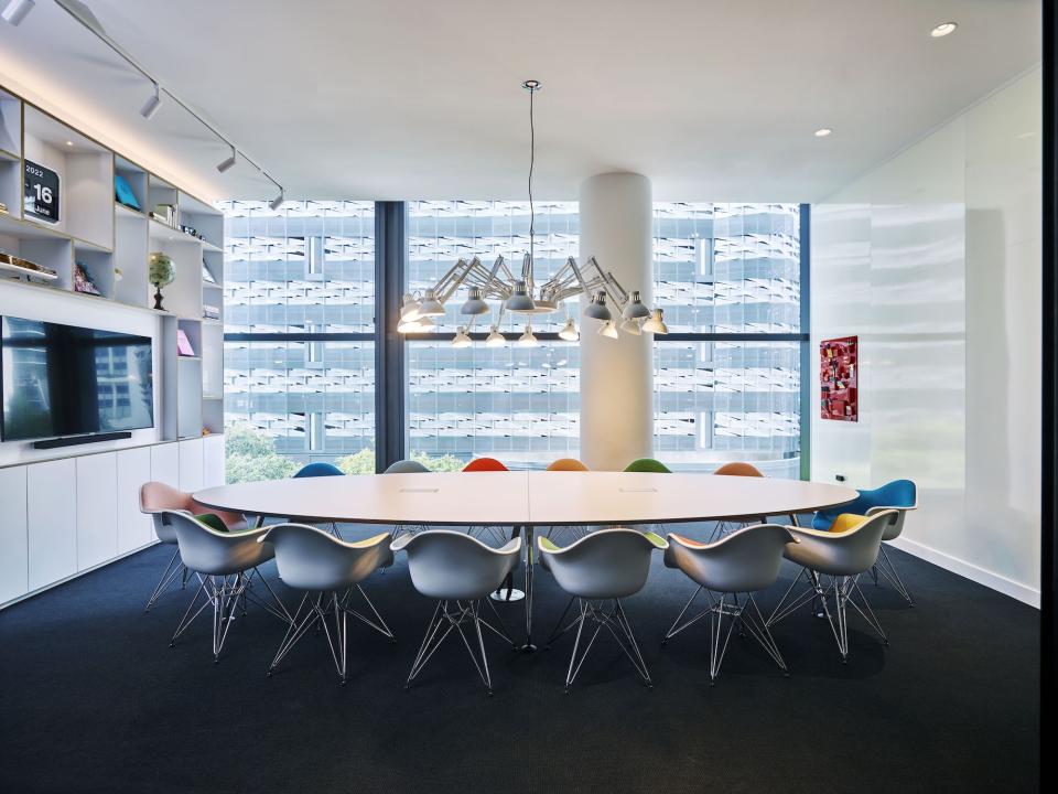 Modern conference room at citizenM Miami featuring a long table, colorful chairs, and large windows.