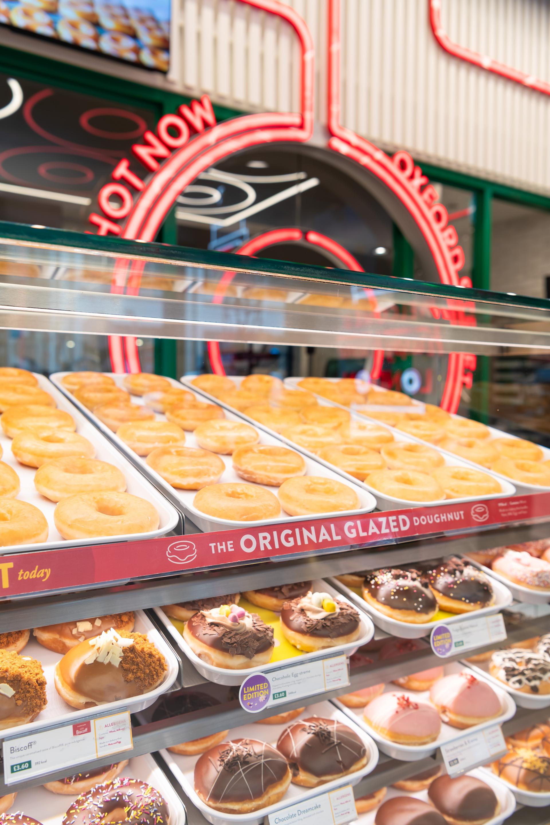 Freshly made Original Glazed and assorted doughnuts display in Krispy Kreme's illuminated London flagship store.