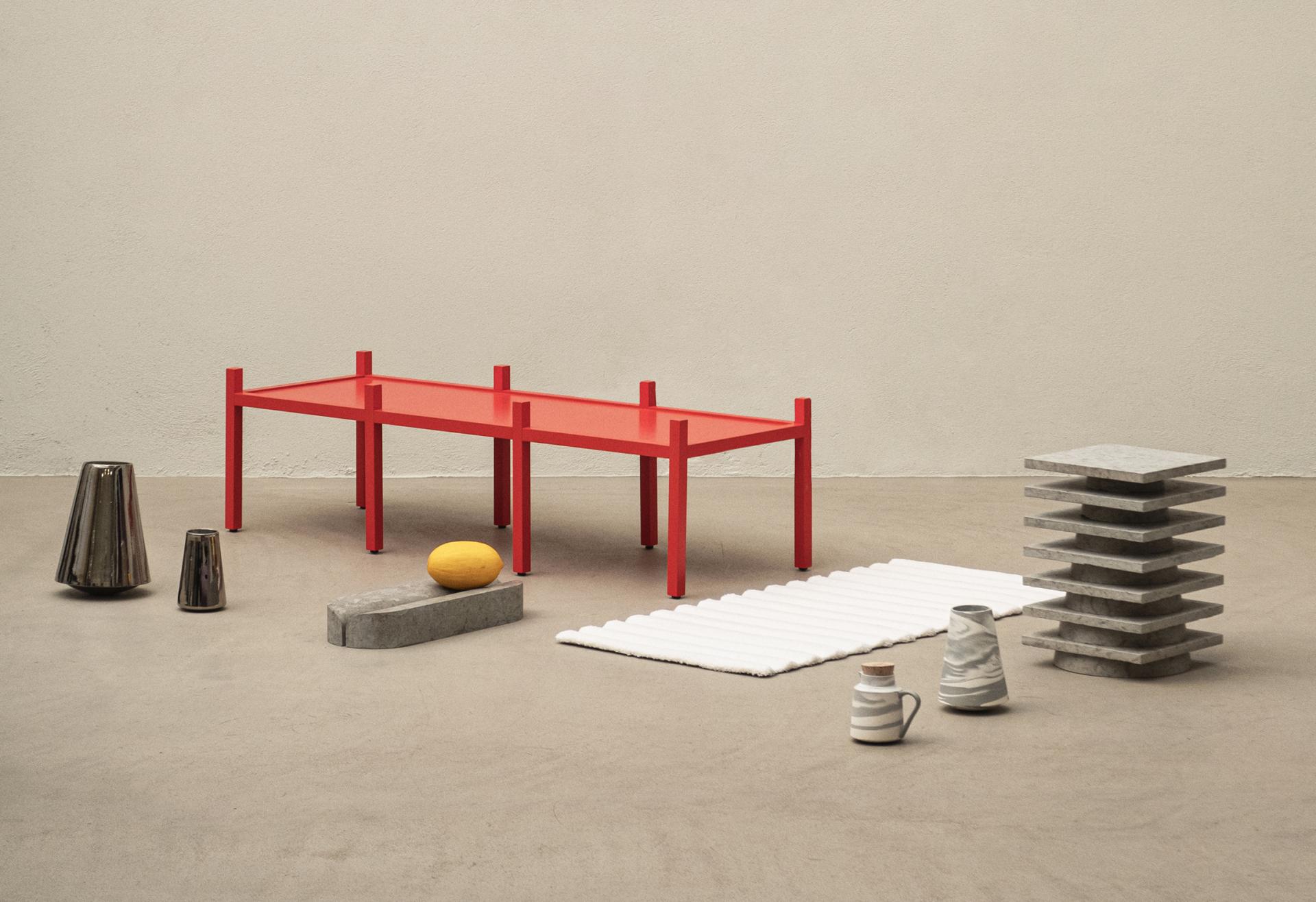 Contemporary red table surrounded by various textured objects, showcasing innovative Baltic design materials.