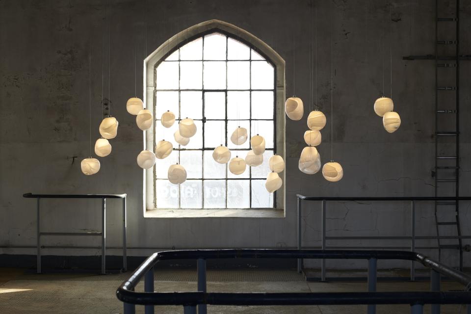 Hanging porcelain light fixtures create an ambient glow in an industrial space, reflecting contemporary German design innovation.