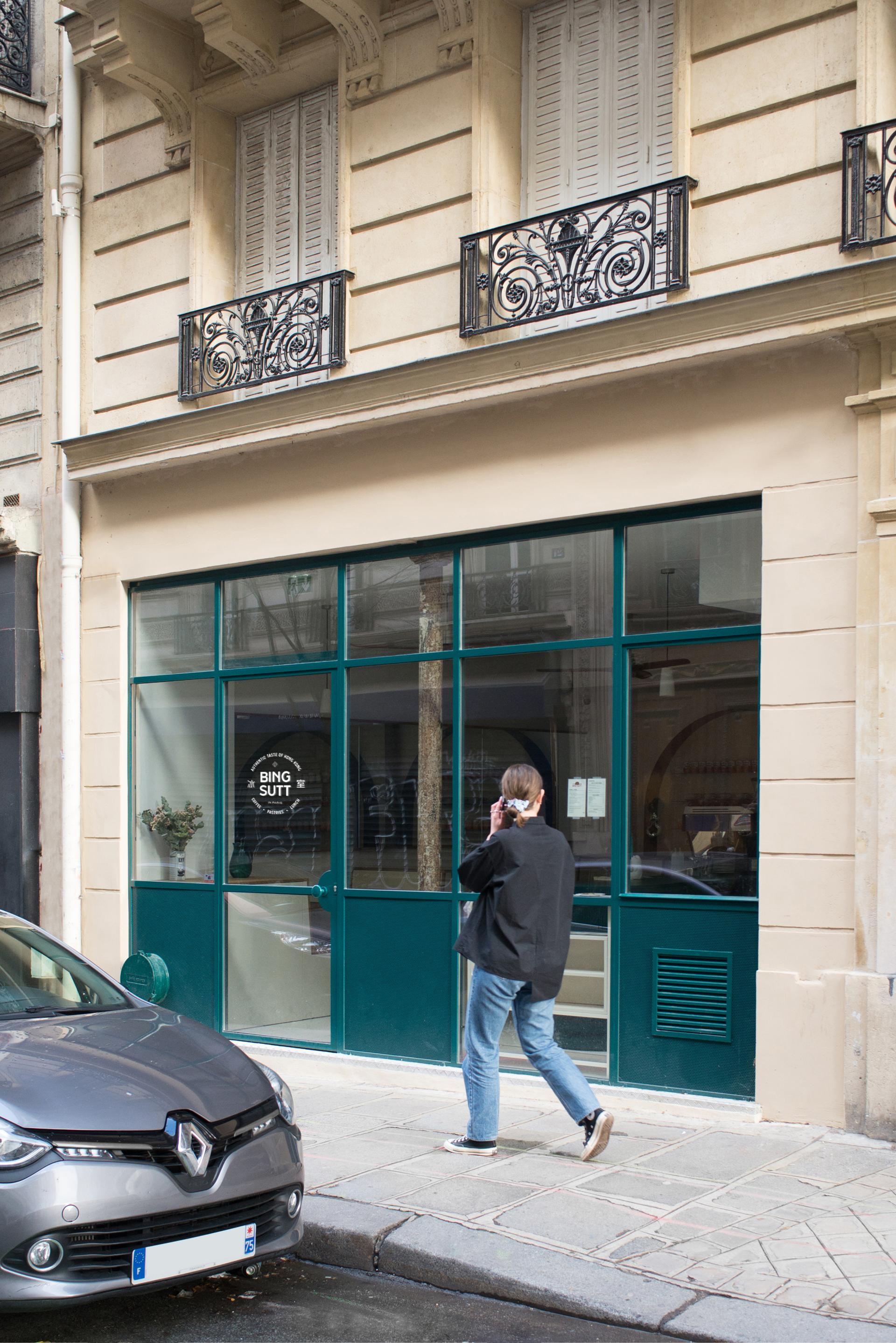 Modern Bing Sutt restaurant facade in Paris, showcasing stylish architecture and a person walking by.