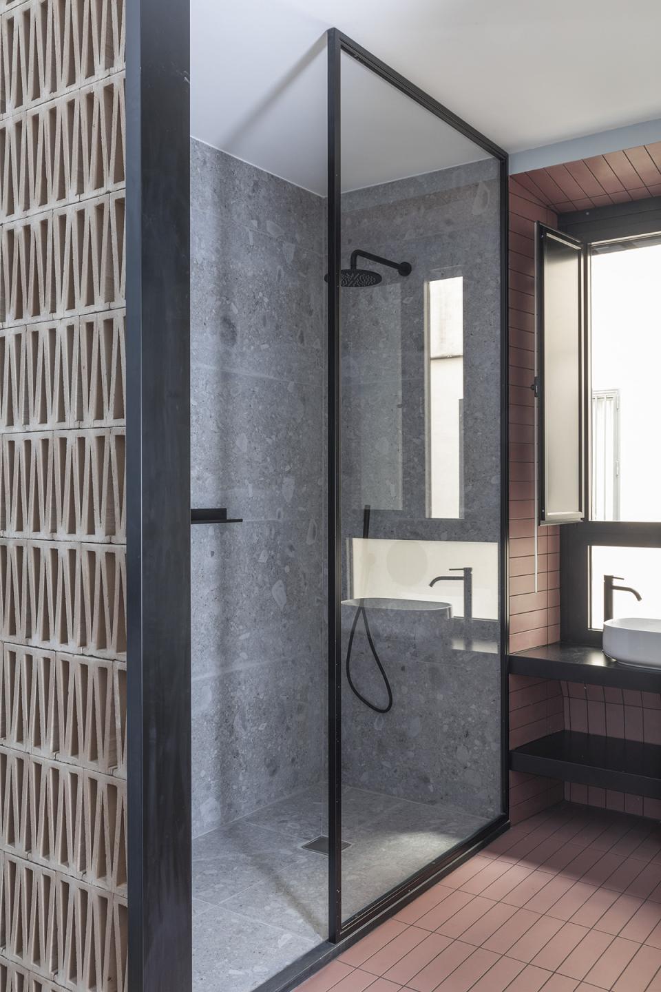 Modern bathroom design featuring a glass shower, stone walls, and a stylish sink in a Trastevere apartment.