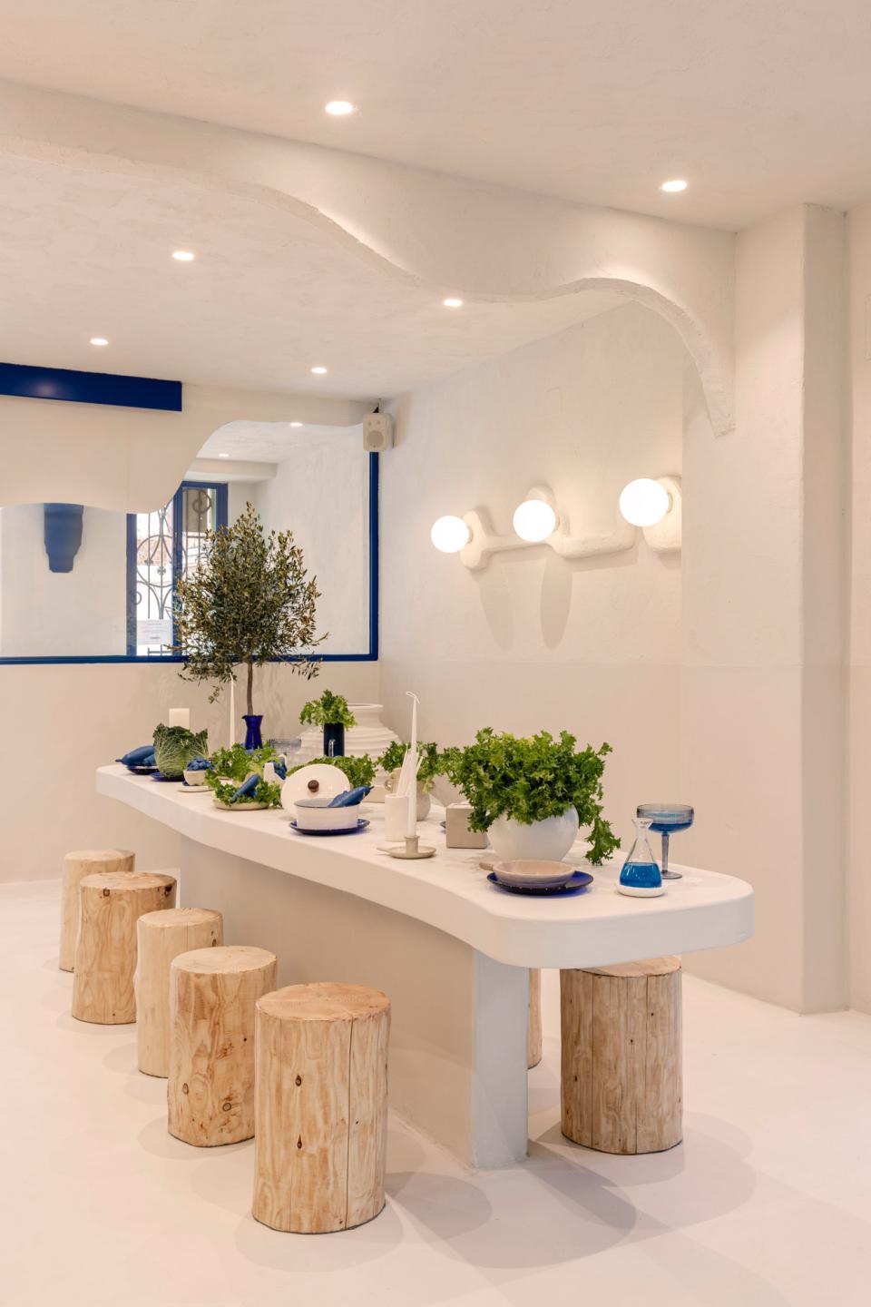 Modern interior design of Egeo restaurant featuring minimalist decor, natural wood seating, and vibrant plant arrangements.