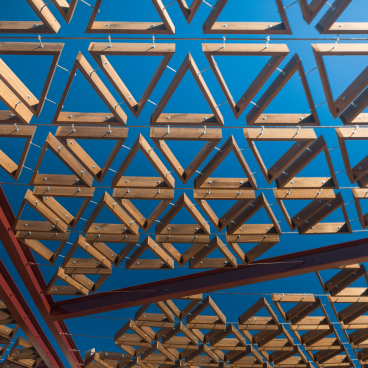 Geometric wooden structure showcasing thermally modified tulipwood against a clear blue sky in Barcelona.