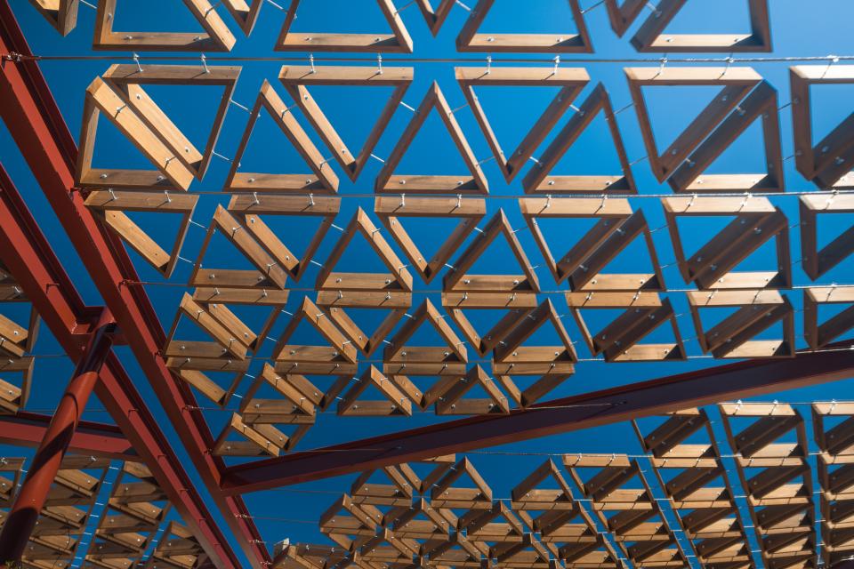 Geometric wooden structure showcasing thermally modified tulipwood against a clear blue sky in Barcelona.