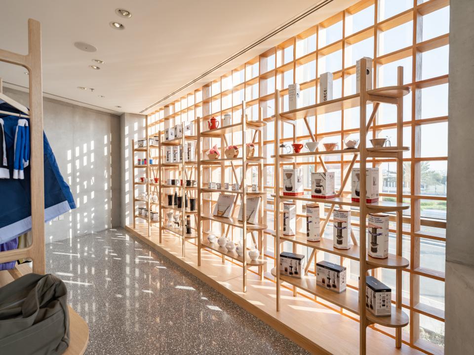 Brightly lit coffee shop interior showcasing wooden shelving with brewing equipment, reflecting a Japandi aesthetic for Brew92.