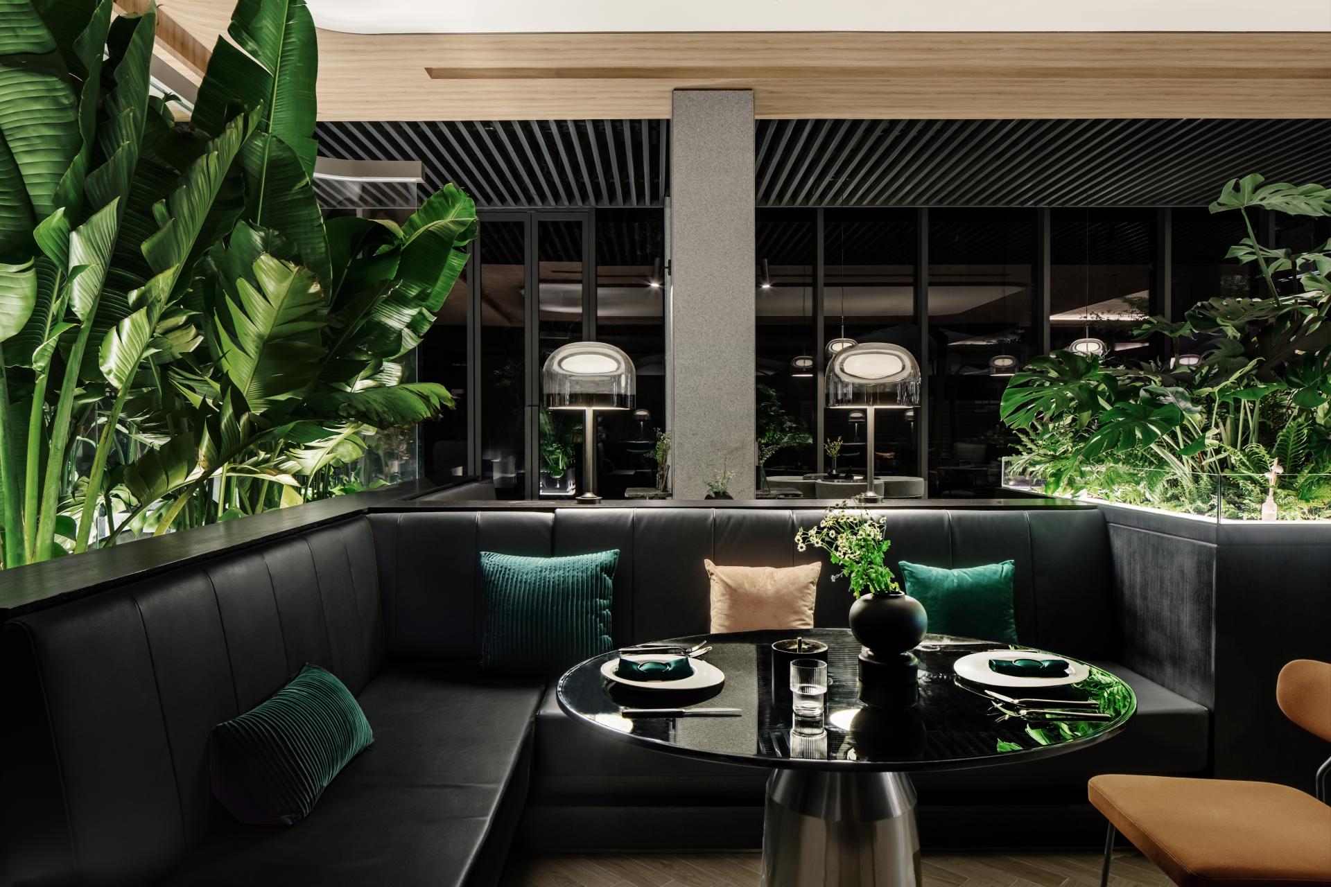 Elegant interior of a nature-themed restaurant featuring lush greenery, modern seating, and artistic decor, inviting relaxation.