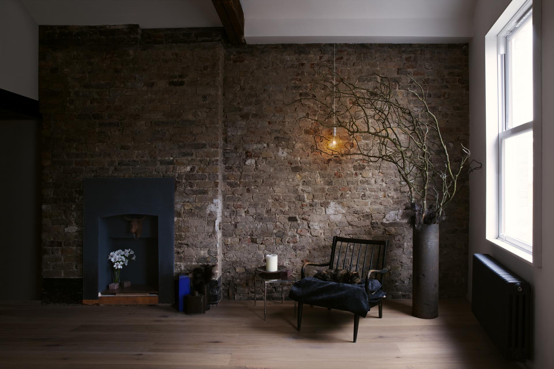 Modern interior design featuring a rustic brick wall, minimalist furniture, and artistic decor elements by THISS studio.