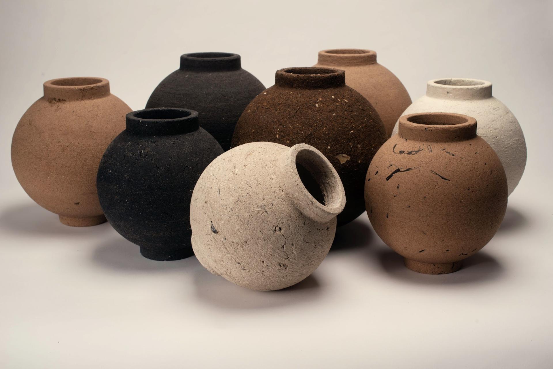 Eight unique, textured ceramic vases in varying earth tones displayed artistically for Material Matters at London Design Festival 2023.