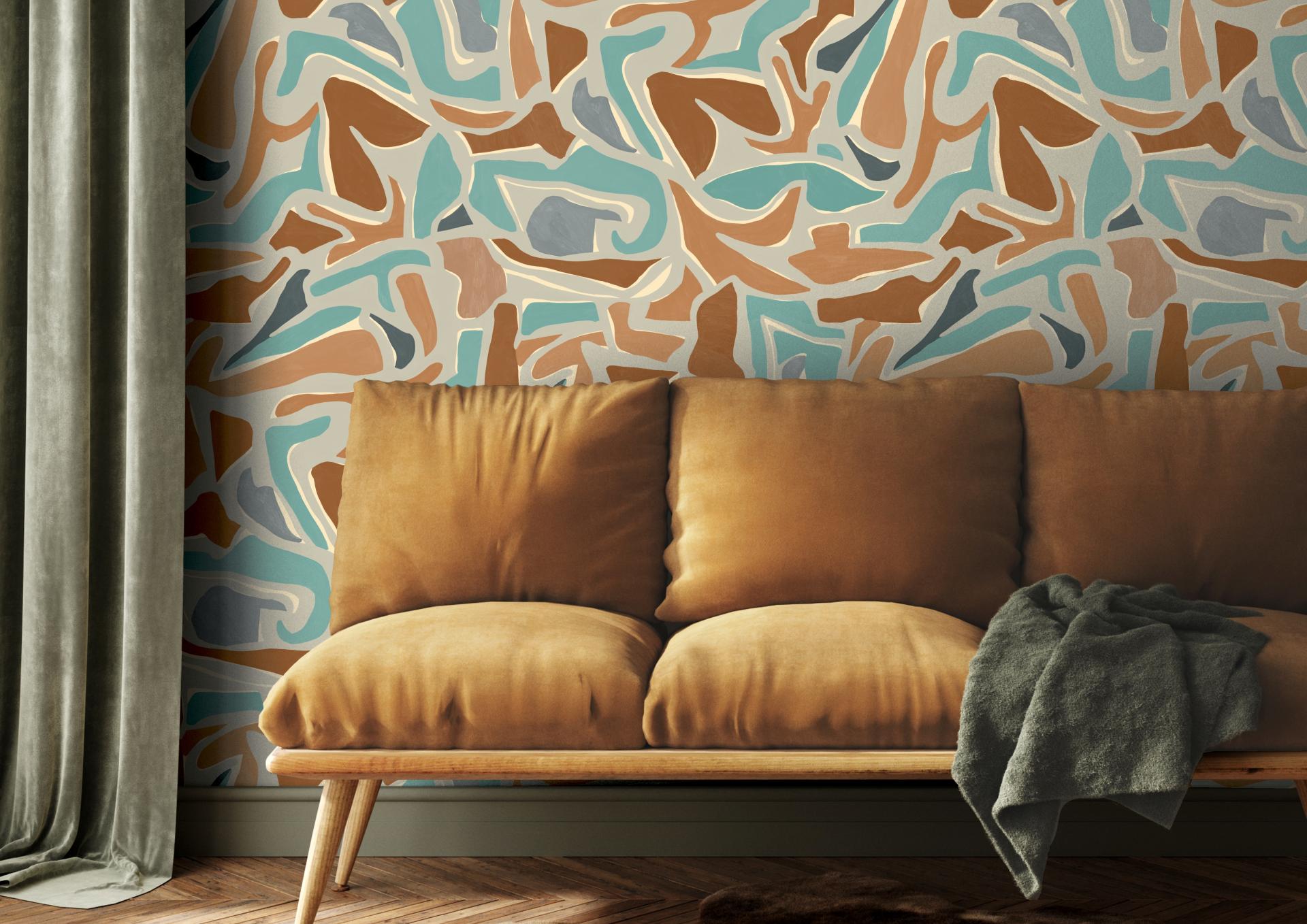 Textured wall featuring abstract patterns in soft colors behind a cozy, mustard-yellow sofa with a grey throw blanket.