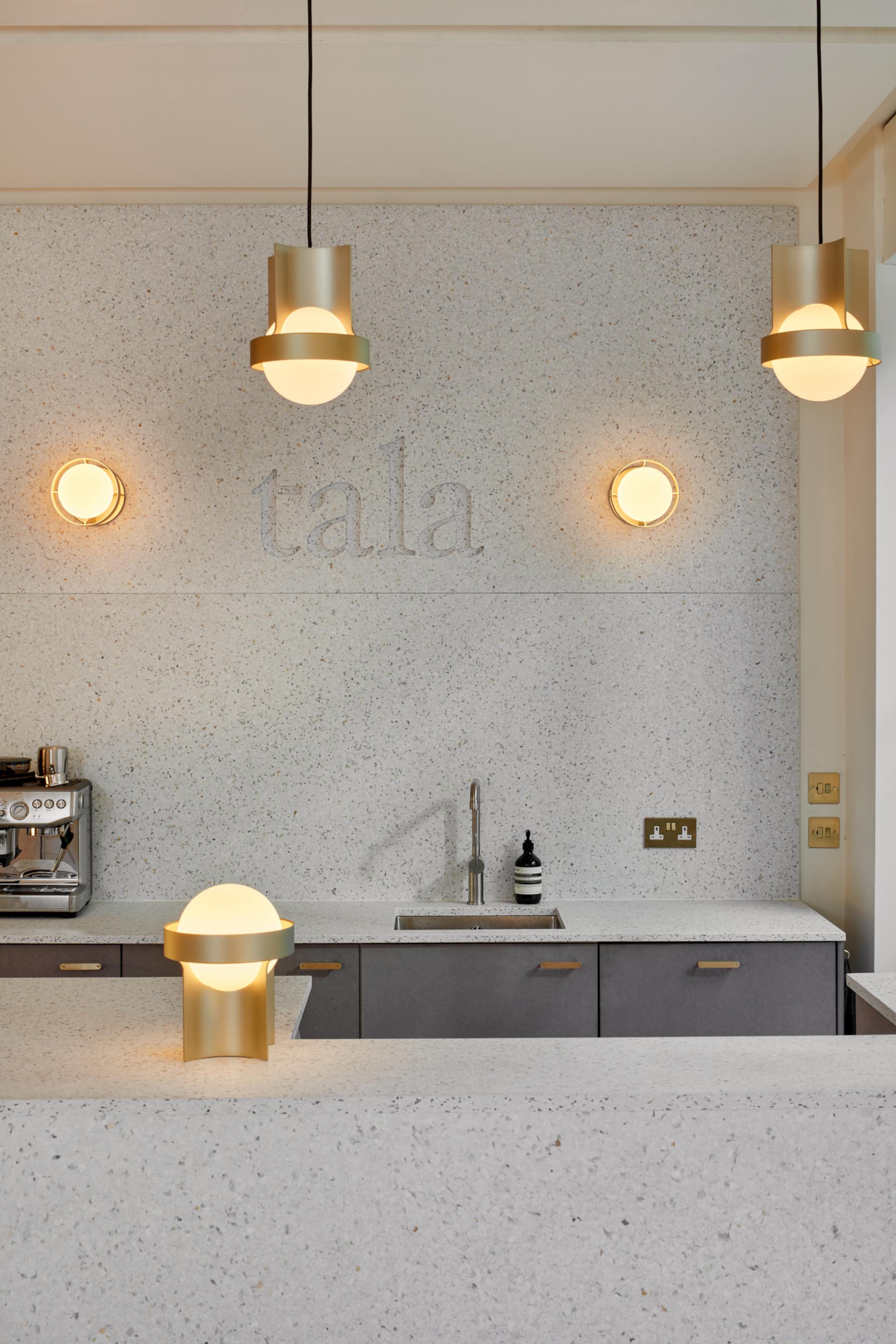 Stylish showroom featuring Tala's sustainable lighting designs against a textured, contemporary wall with sleek kitchen elements.