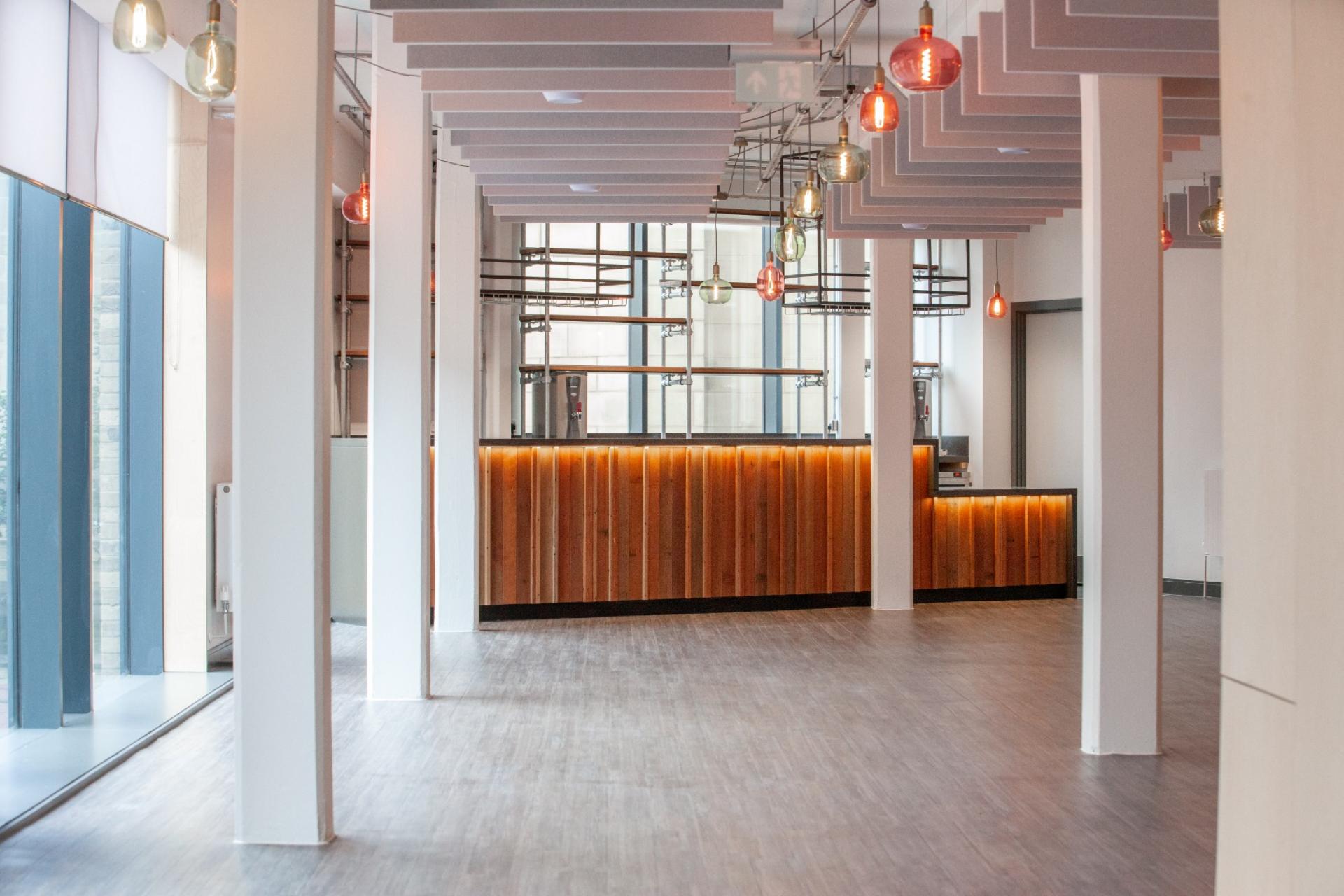 Modern interior design showcasing a spacious area with warm wood accents, colorful pendant lights, and large windows.