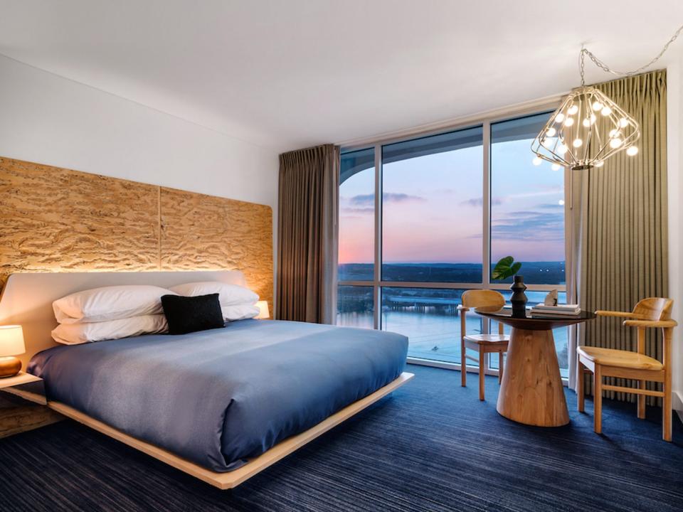 Stylish mid-century hotel room designed by Sean Knibb, featuring natural materials, pale pinks, and a stunning lake view.