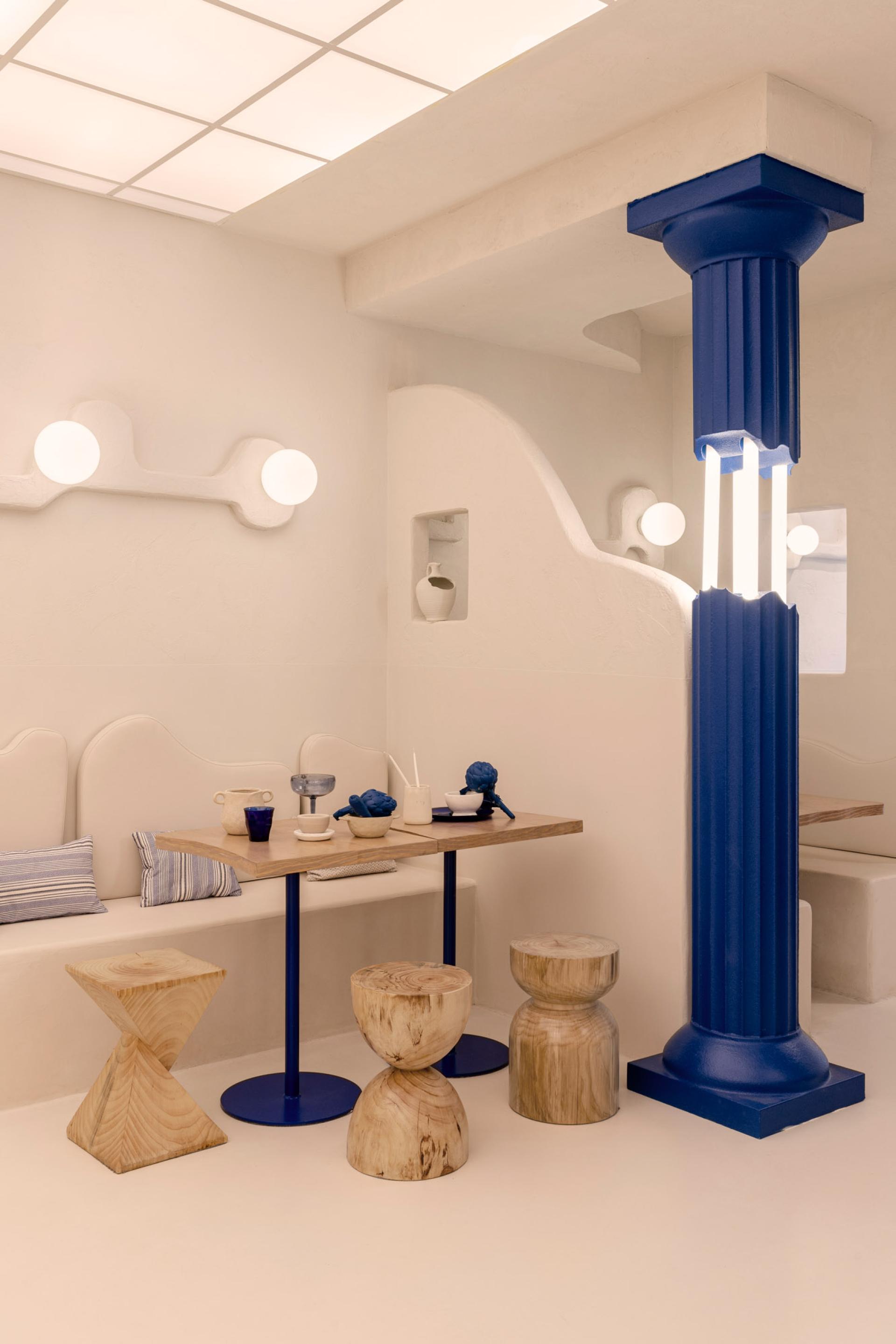 Modern Greek restaurant interior featuring minimalist design, wooden furniture, and blue accents, reflecting Egeo's fusion of tradition and technology.