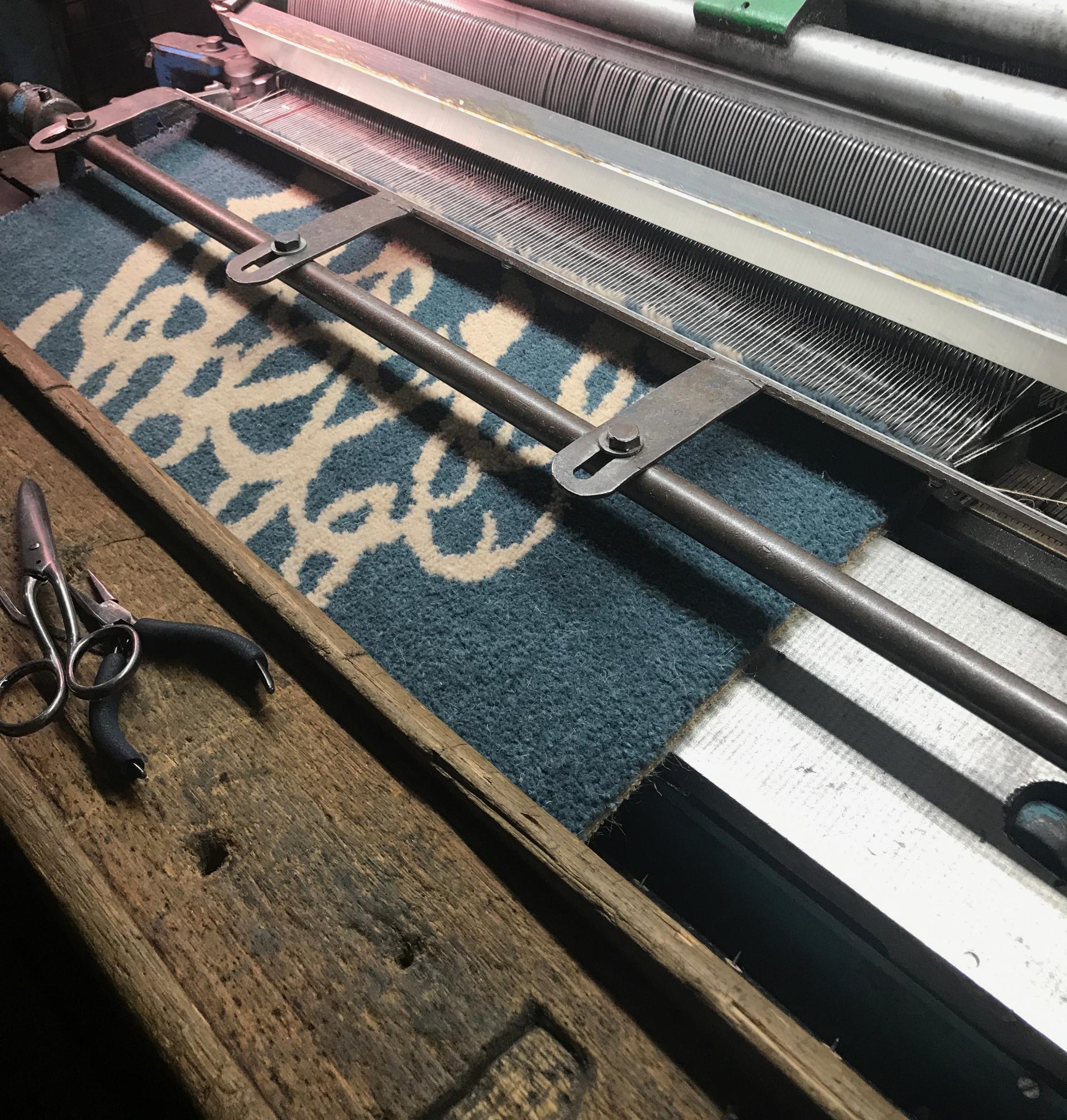 Wool fabric being woven on a traditional loom, showcasing British wool's journey in textile design.